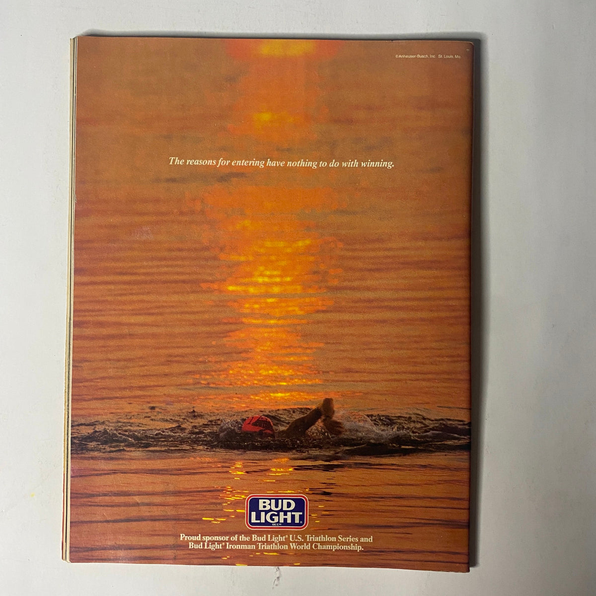 Back cover of Triathlete Magazine July 1987 No. 47 with an advertisement for Bud Light, featuring a serene image of a swimmer in sunset, emphasizing the sport's connection to enjoyment and competition.