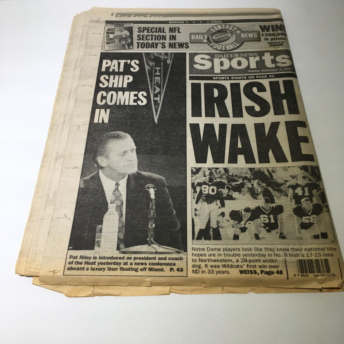 A vintage newspaper featuring an article titled 'NY Daily News: Sept 3 1995 Riley Roars,' showcasing Pat Riley at a press conference introducing himself as president and coach of the Miami Heat.