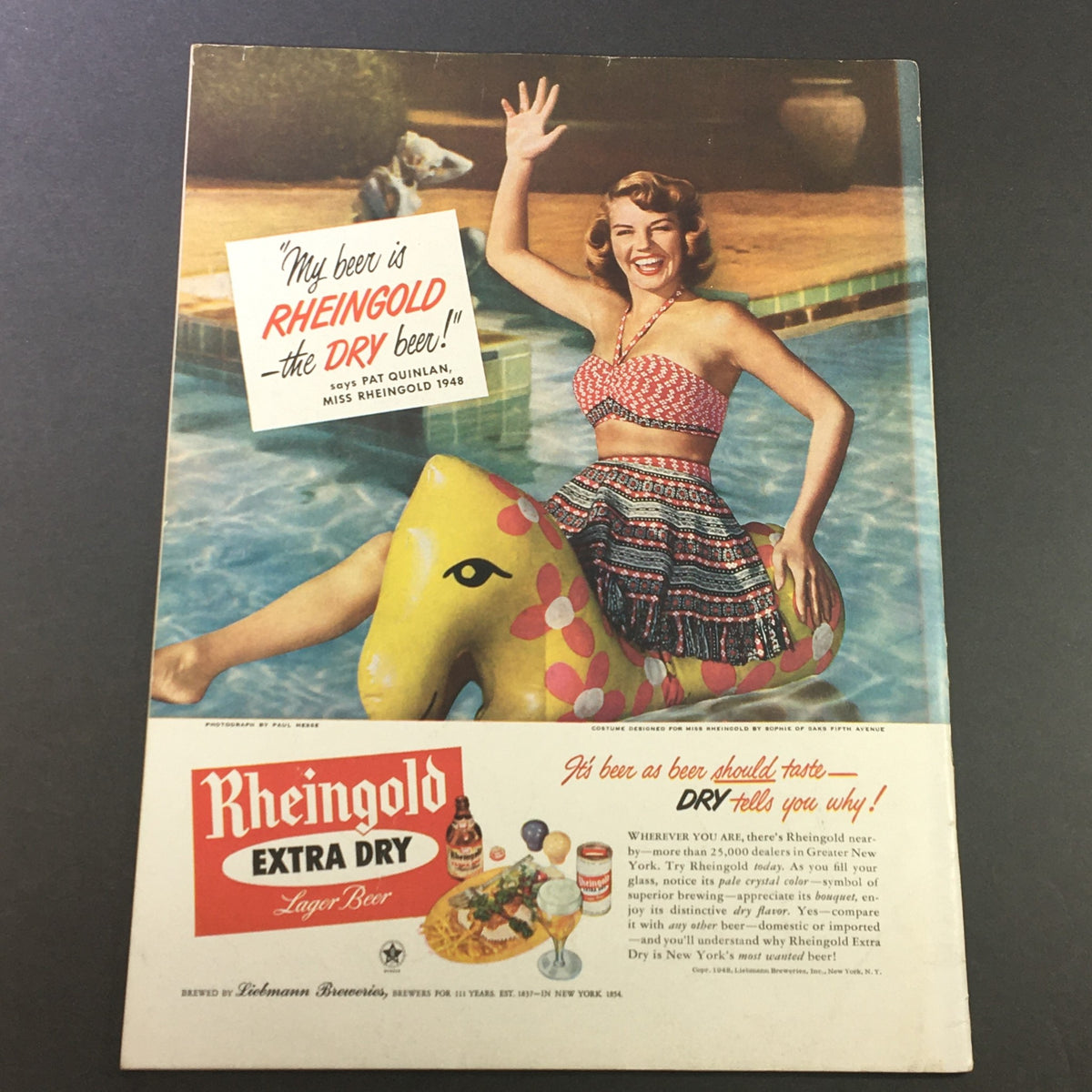 Advertisement from VTG Gourmet The Magazine of Good Living August 1948 showcasing a cheerful model promoting Rheingold Extra Dry beer at a poolside setting.
