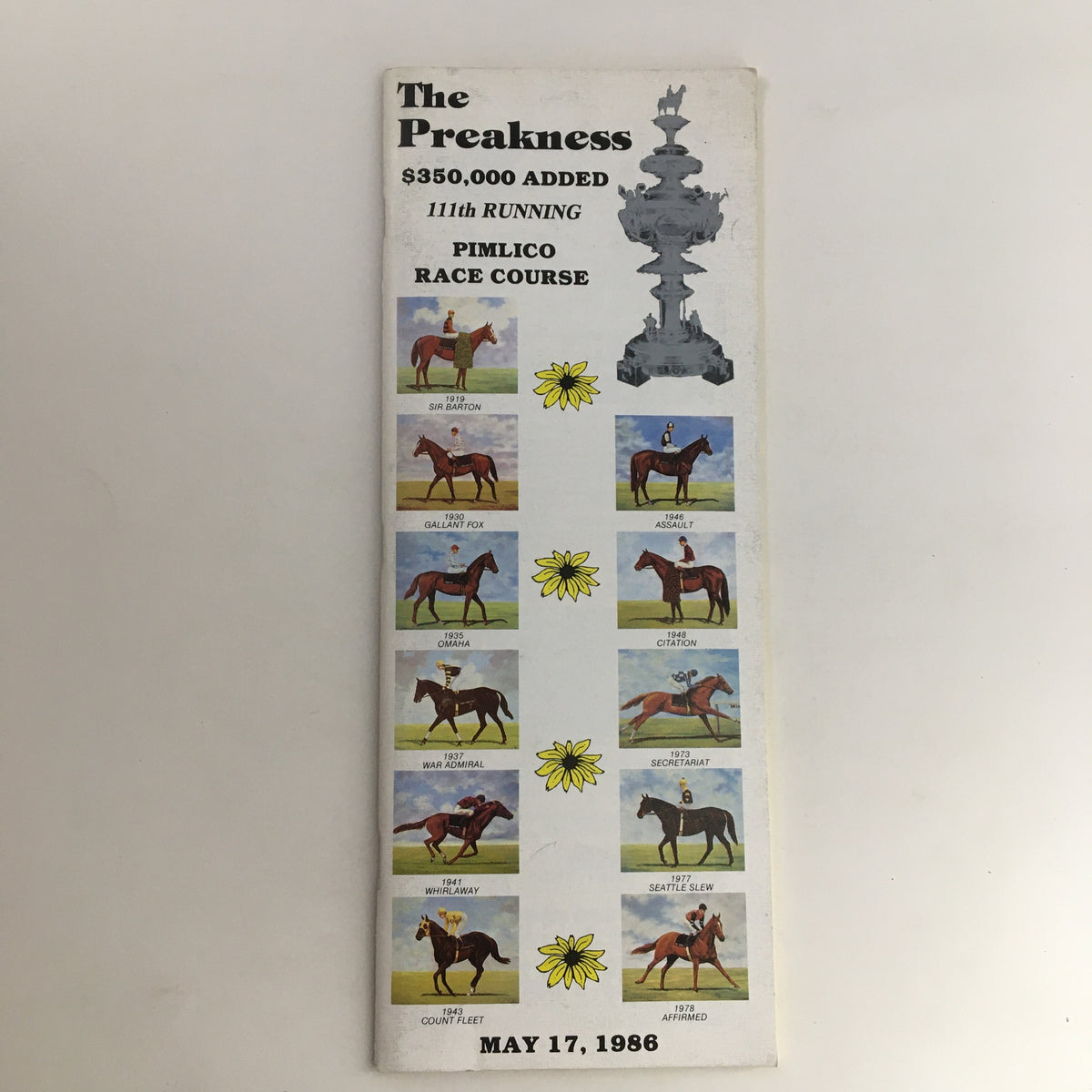 Cover of the 1986 Pimlico Race Course The Preakness Official Souvenir Program featuring a detailed illustration of notable horses and the Pimlico trophy.