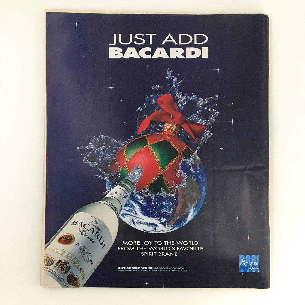 Crisp image of a vintage advertisement for Bacardi Rum featuring a festive Christmas ornament, conveying the slogan 'Just Add Bacardi'. This ad adds a unique charm to the Rolling Stone Magazine December 23, 1993 Cindy Crawford Cover & Billy Joel.
