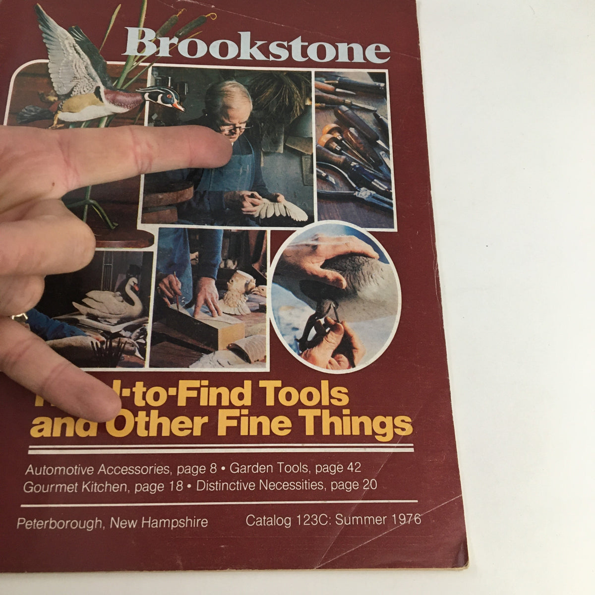 Close-up of the 1976 Brookstone Hard-To-Find-Tools and Other Fine Things Catalog 123C cover with a hand pointing at the title.