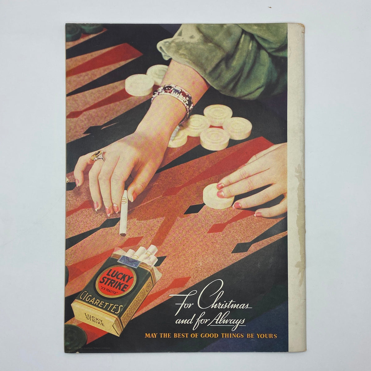 Vintage advertisement for Lucky Strike cigarettes featuring a woman's hand and a pack of cigarettes, set against a colorful patterned background. The ad states 'For Christmas and for Always' and promotes holiday sentiments.