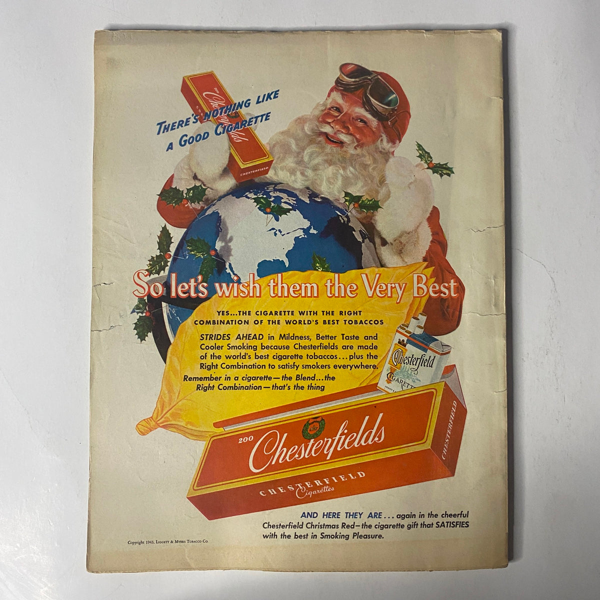 Vintage advertisement for Chesterfield cigarettes featured on the back cover of Radio Mirror Magazine December 1943, showcasing a Santa Claus theme with a globe.