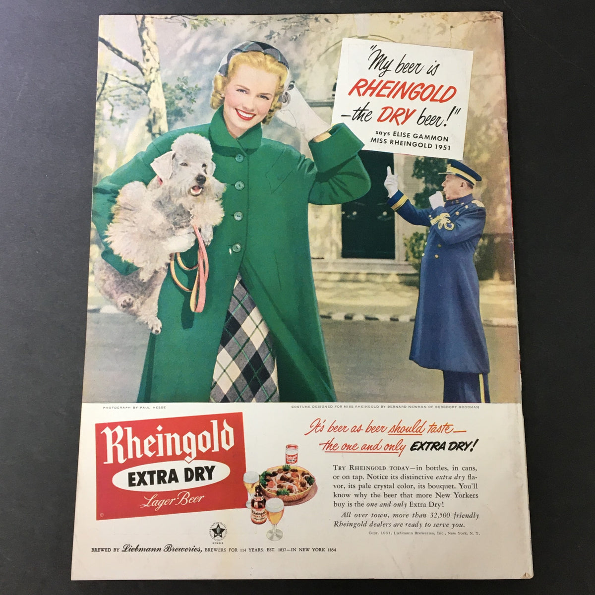 Vintage advertisement for Rheingold Extra Dry Lager Beer from 1951, showcasing a glamorous woman in a green coat holding a dog, capturing mid-20th century fashion and lifestyle.