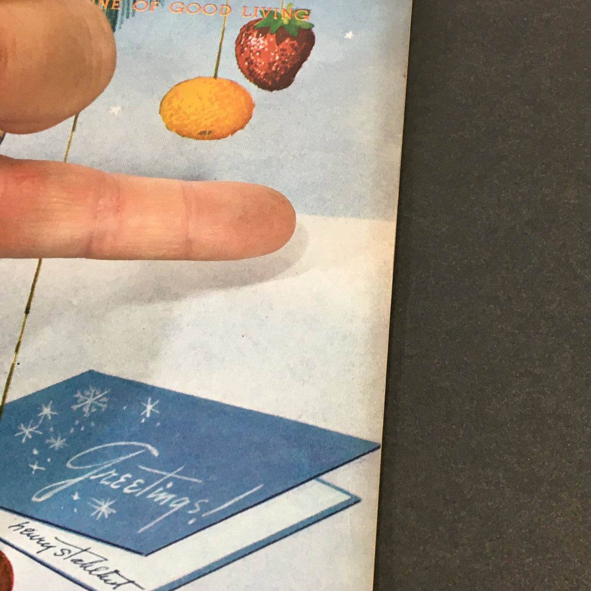 Detailed view of the greetings card on the cover of VTG Gourmet: The Magazine of Good Living, December 1952, showcasing holiday decorations and colorful fruits.