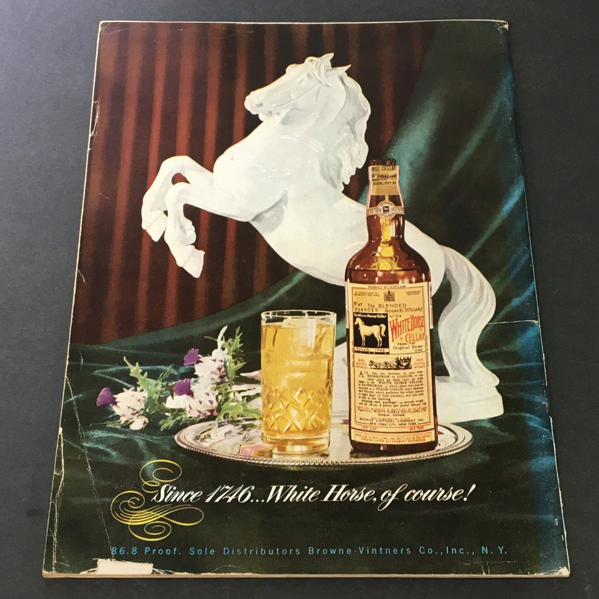 Back cover of VTG Gourmet The Magazine of Good Living November 1953, featuring a white horse statue and a whiskey bottle against a rich backdrop, emphasizing the luxurious themes of the era.