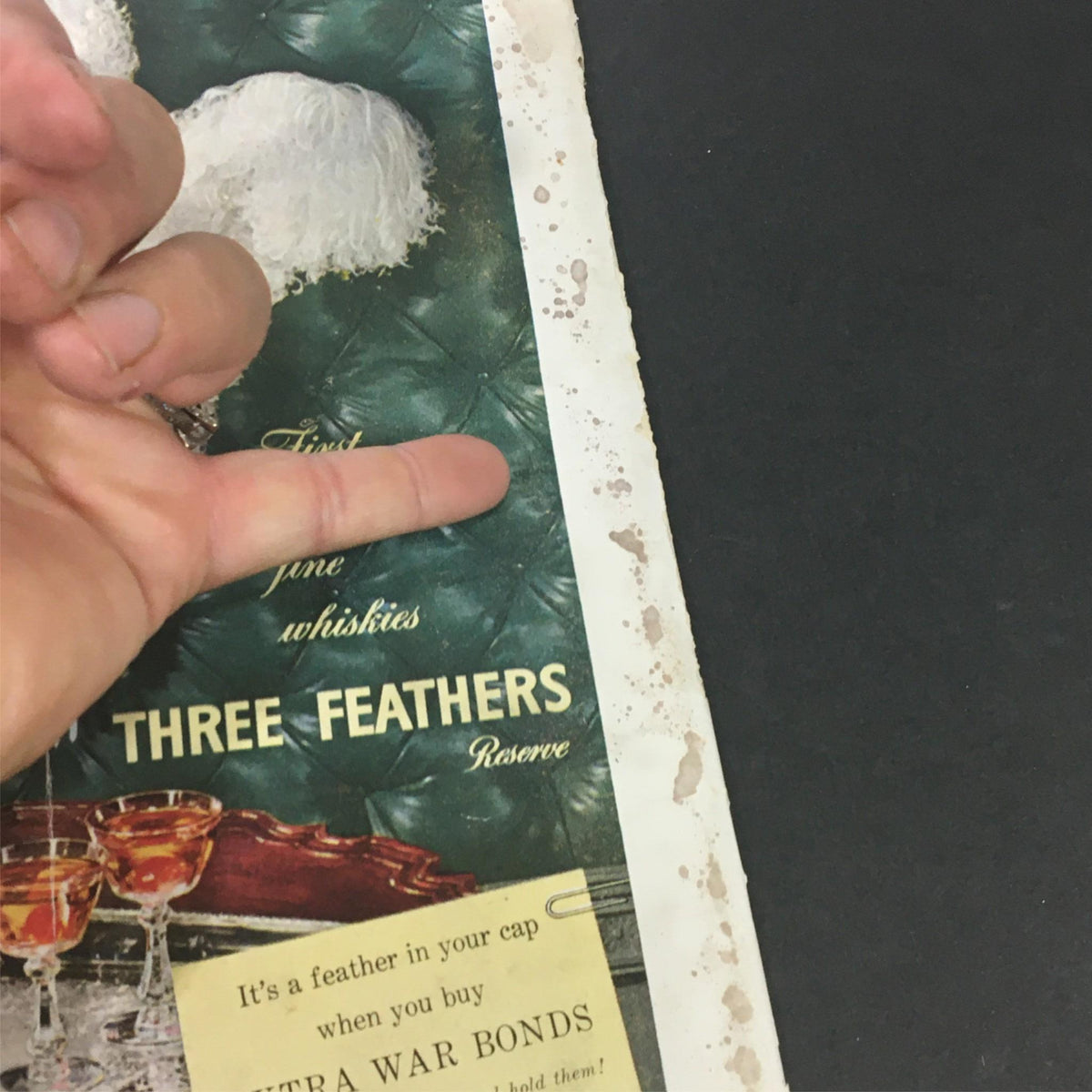 Close-up of a vintage page from the September 1944 issue of VTG Gourmet: The Magazine of Good Living featuring an advertisement for Three Feathers whisky with decorative glassware.