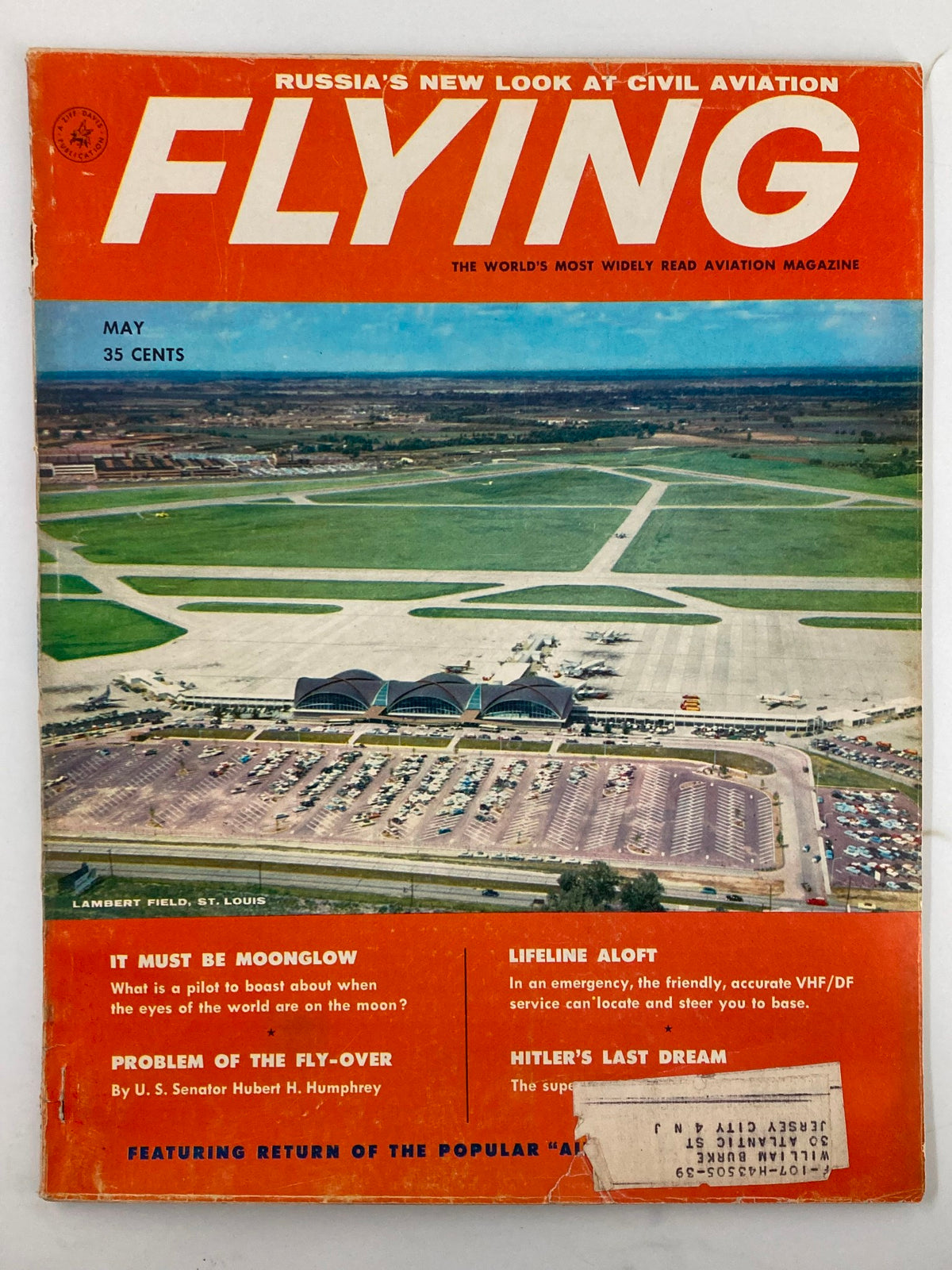 Cover of VTG Flying Magazine May 1958 featuring Lambert Field, St. Louis and article 'Hitler's Last Dream', showcasing aviation history with a vibrant orange background.