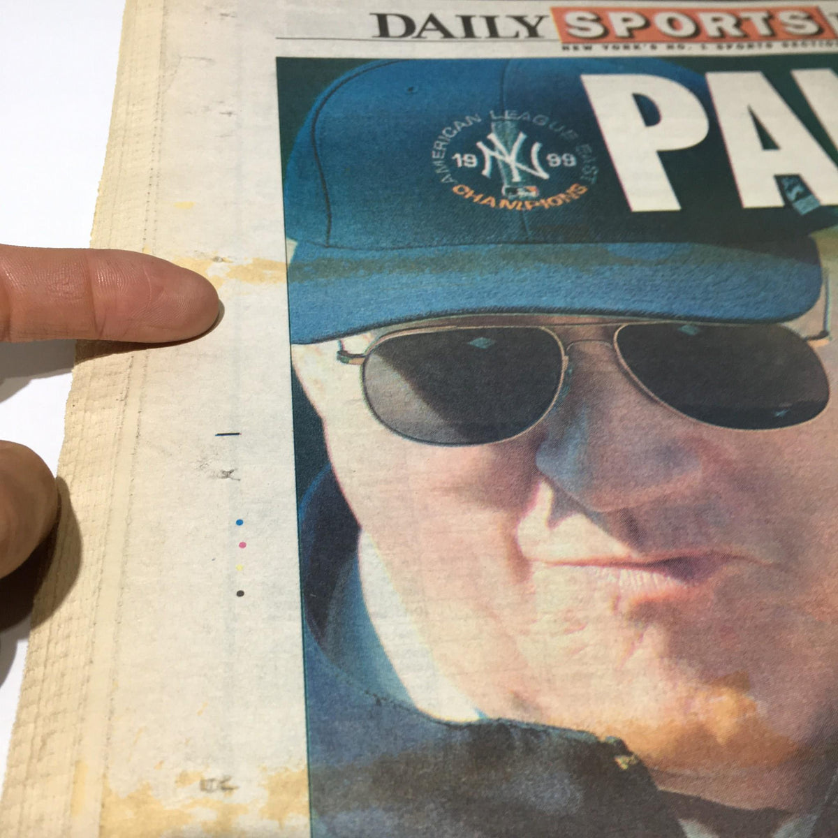 Close-up view of the front page of NY Daily News from July 29, 2003, showing a man in sunglasses and a New York Yankees cap, highlighting a water stain along the edge. This image captures details relevant to the newspaper's condition for collectors.
