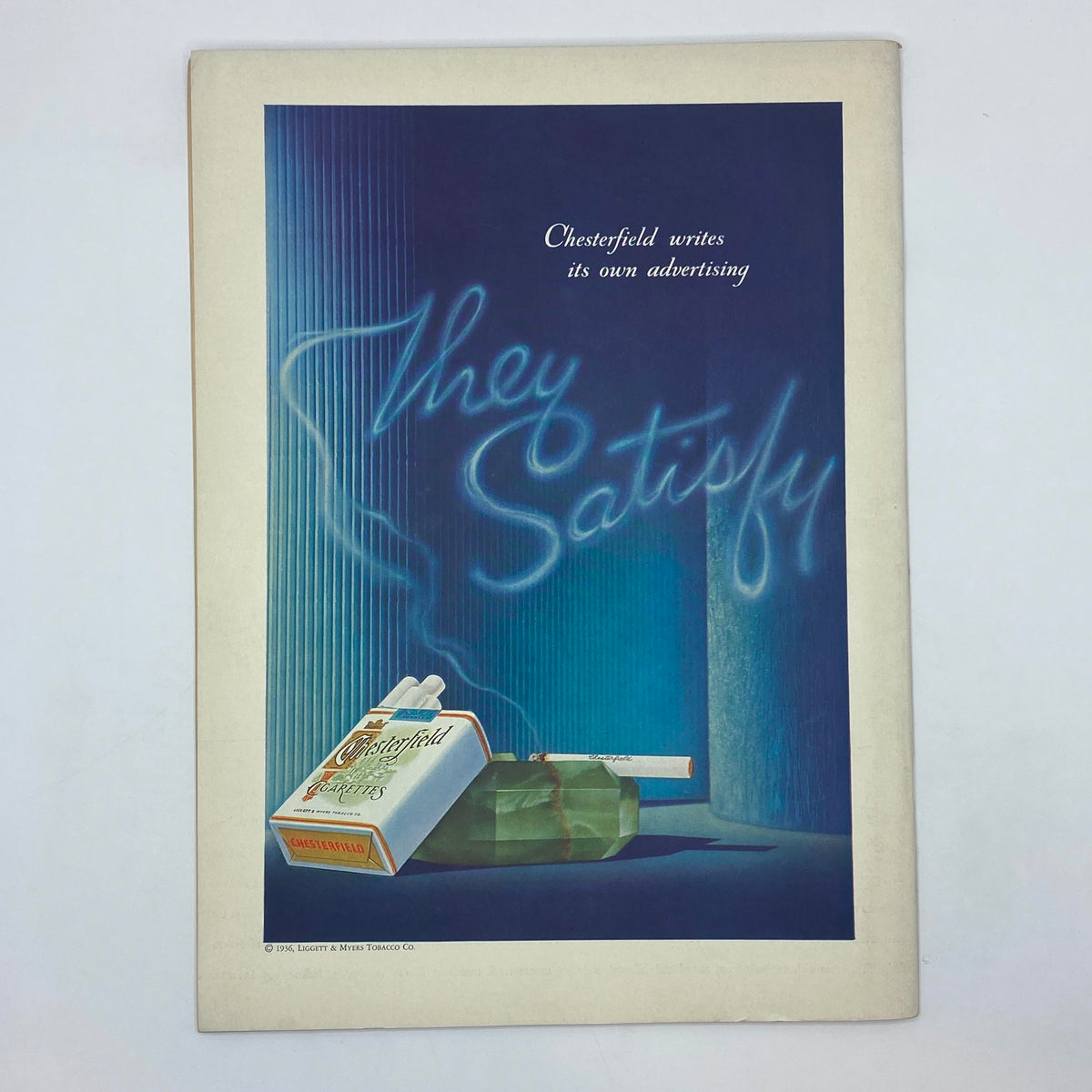The New Yorker Complete Magazine May 2, 1936 featuring an advertising page for Chesterfield cigarettes, showcasing a stylized layout with a cigarette pack and dramatic neon text stating 'They Satisfy'.