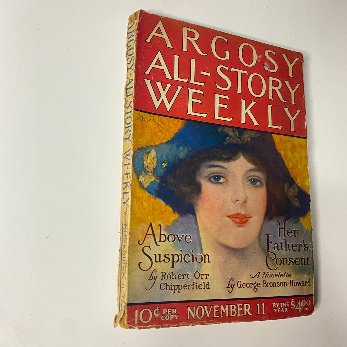Cover of Argosy All-Story Weekly magazine from November 11, 1922, featuring the title 'Above Suspicion' by Robert Orr Chipperfield, with a colorful illustration of a woman wearing a hat.