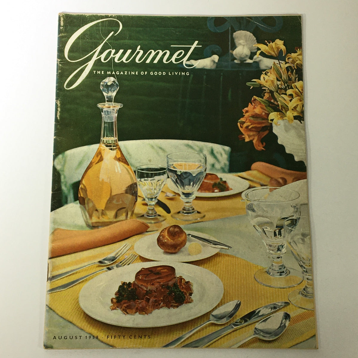 Cover of VTG Gourmet: The Magazine of Good Living, August 1958, featuring a beautifully set dining table with elegant glassware, a colorful tablecloth, and gourmet dishes, promoting the theme of 'The Solid Gold Fruit'.