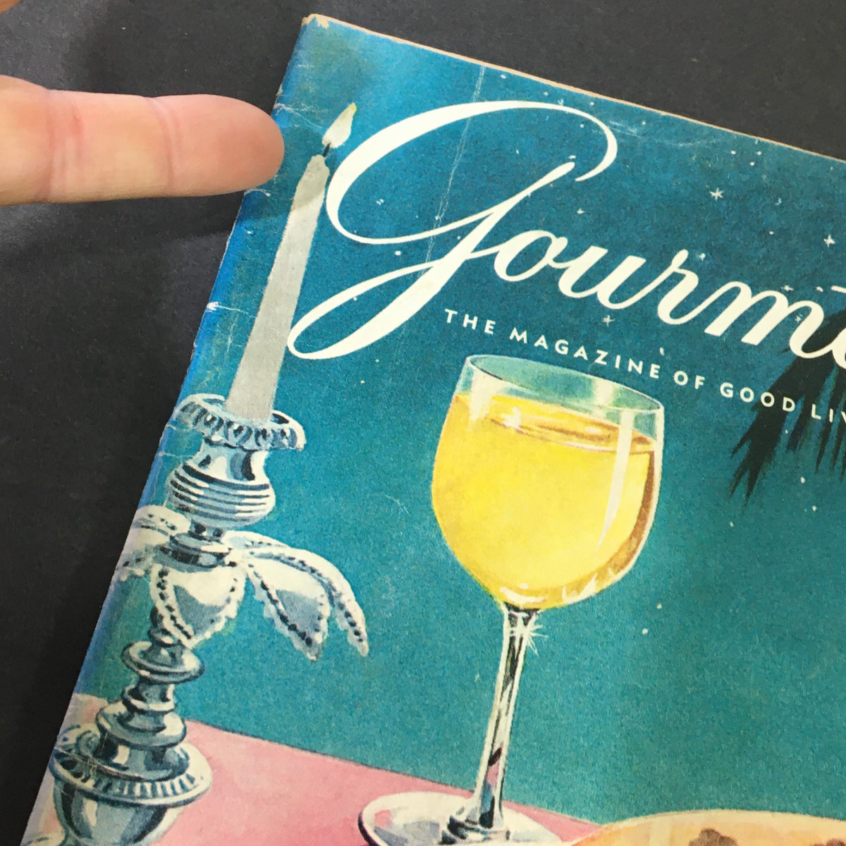 Close-up view of the cover of VTG Gourmet: The Magazine of Good Living, August 1959, showcasing the title and a candle alongside a glass of yellow drink.