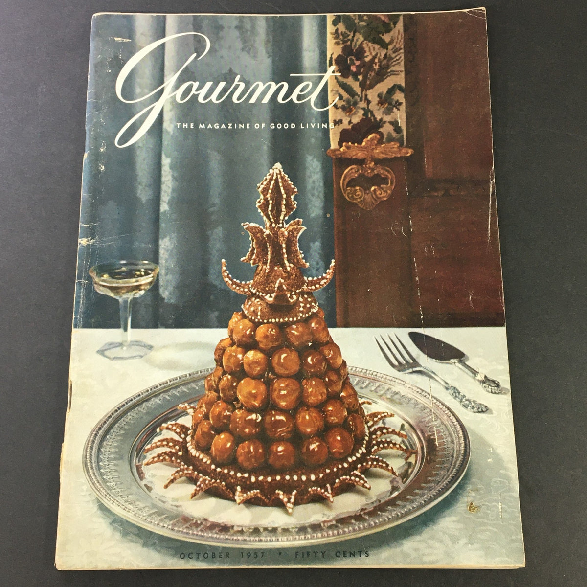 VTG Gourmet The Magazine of Good Living, October 1957 issue cover featuring a decorative dessert presentation on a plate with a champagne glass, celebrating fine dining and gourmet living.