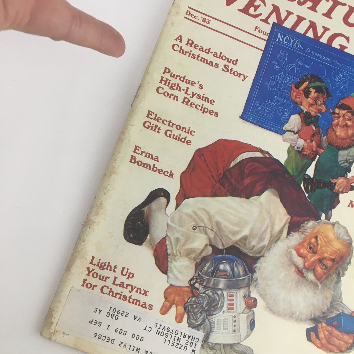 Close-up of The Saturday Evening Post December 1983 cover, highlighting sections with articles like 'Electronic Gift Guide' and 'Erma Bombeck', along with illustrations of festive characters.