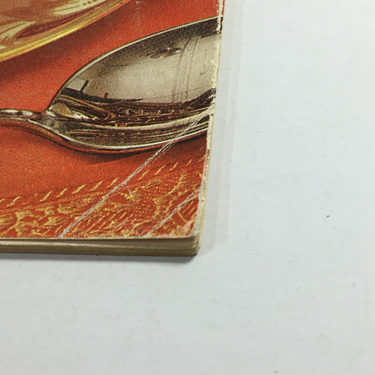 Close-up of the edge of VTG Gourmet The Magazine of Good Living July 1962 showing minor wear, featuring a spoon and intricate table texture.