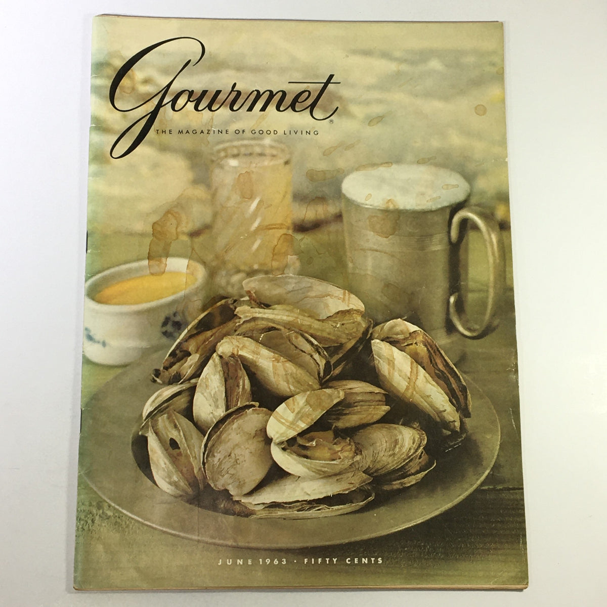 Cover of VTG Gourmet The Magazine of Good Living June 1963, featuring a plate of opened clams, a yellow sauce, and a silver mug, showcasing vintage culinary elegance.