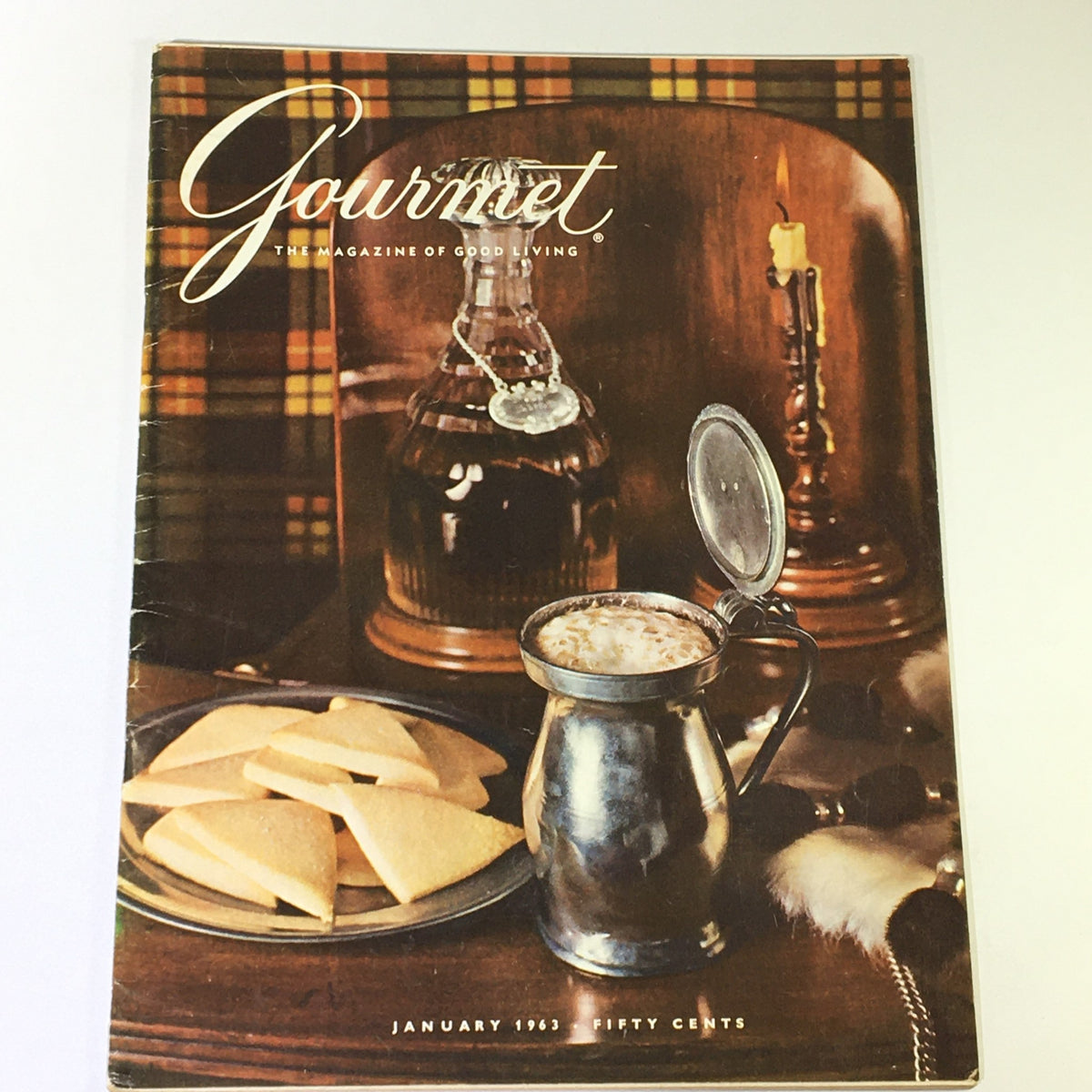Cover of VTG Gourmet: The Magazine of Good Living, January 1963, featuring a silver mug with a drink and butter cookies on a plate, set against a cozy Highland backdrop.