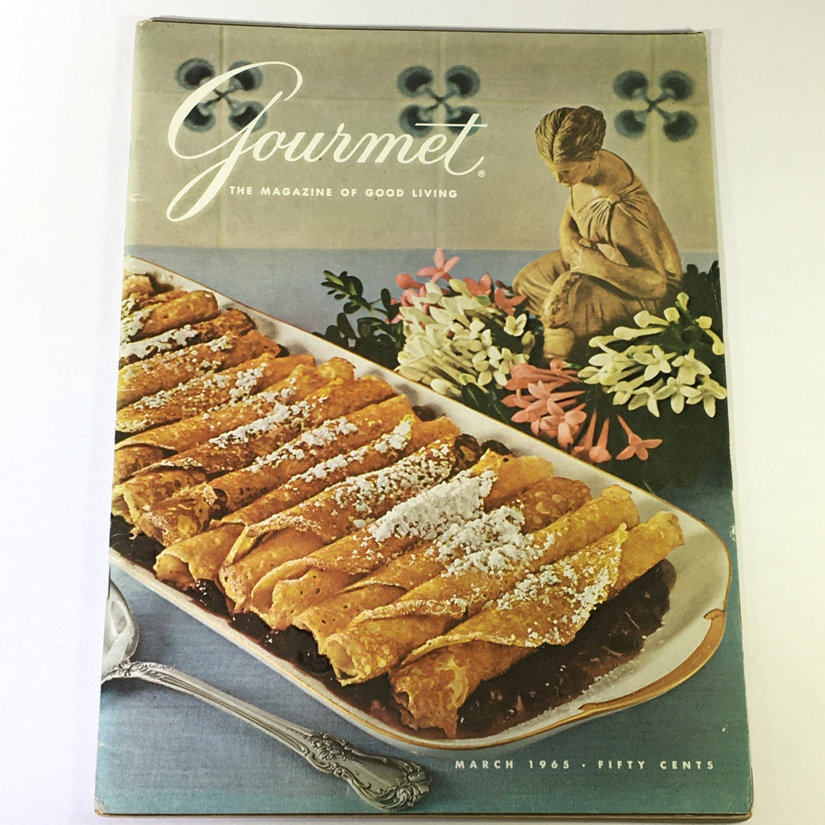 Cover of VTG Gourmet, The Magazine of Good Living, March 1965 featuring a stunning presentation of gourmet crepes, with a decorative statue and floral arrangement in the background.