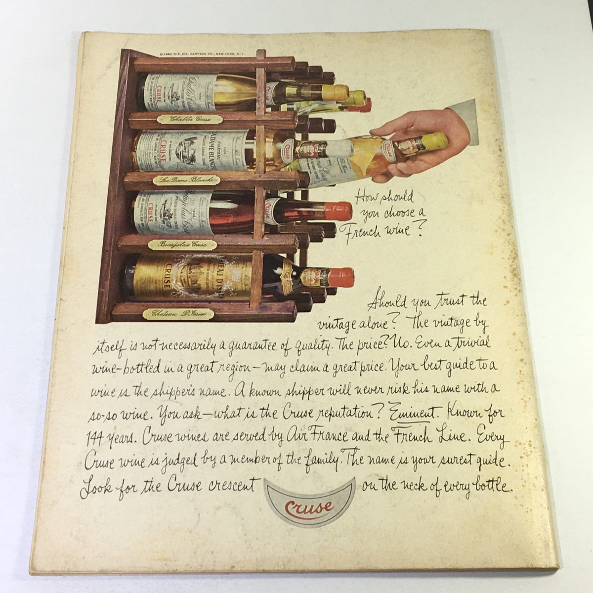Back cover of VTG Gourmet The Magazine of Good Living July 1968 showcasing a vintage wine rack filled with various wine bottles and a hand reaching for a bottle.