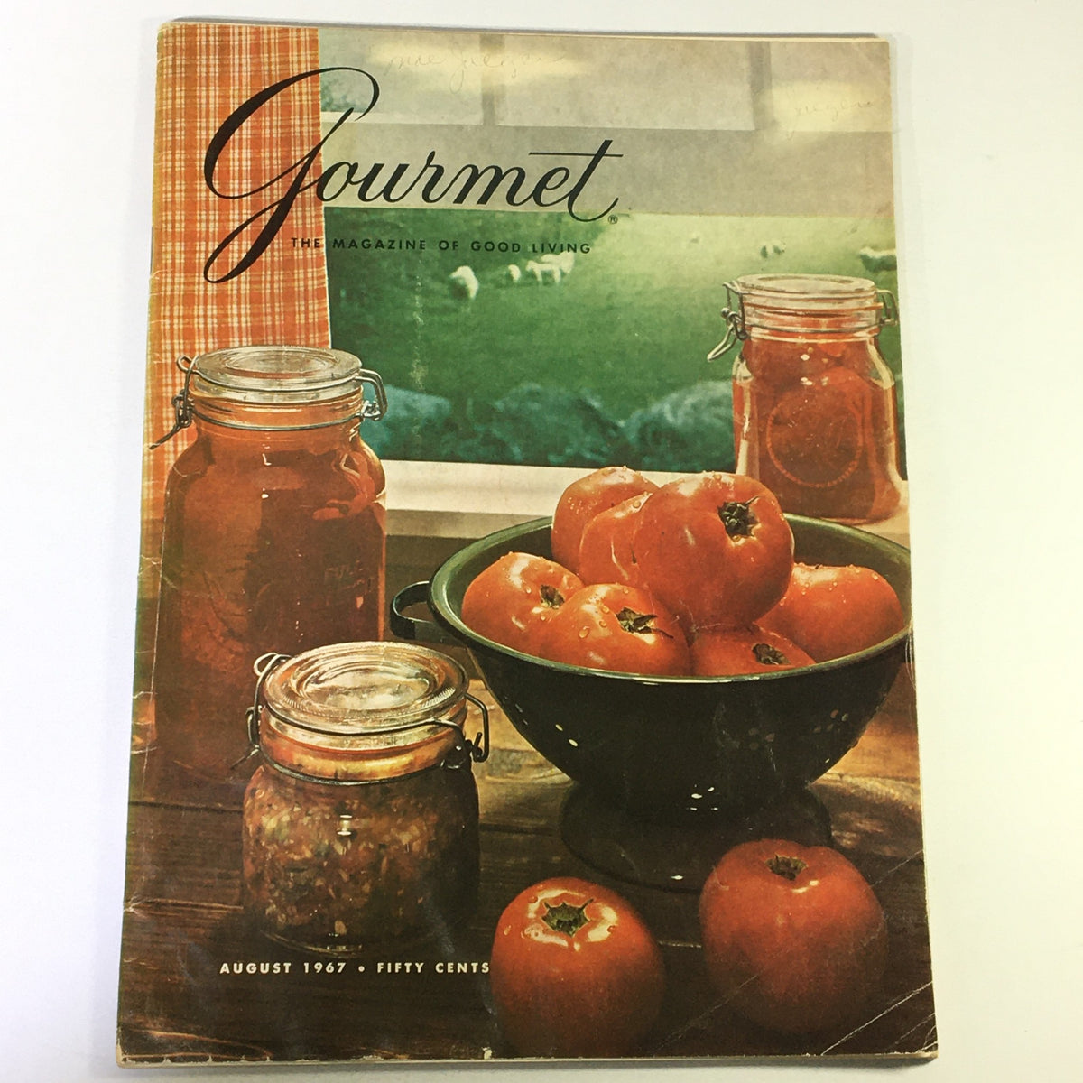 Cover of VTG Gourmet The Magazine of Good Living August 1967 featuring ripe tomatoes in a bowl, jars of preserved tomatoes, and a scenic background of green grass. A historical piece celebrating tomato-based recipes.