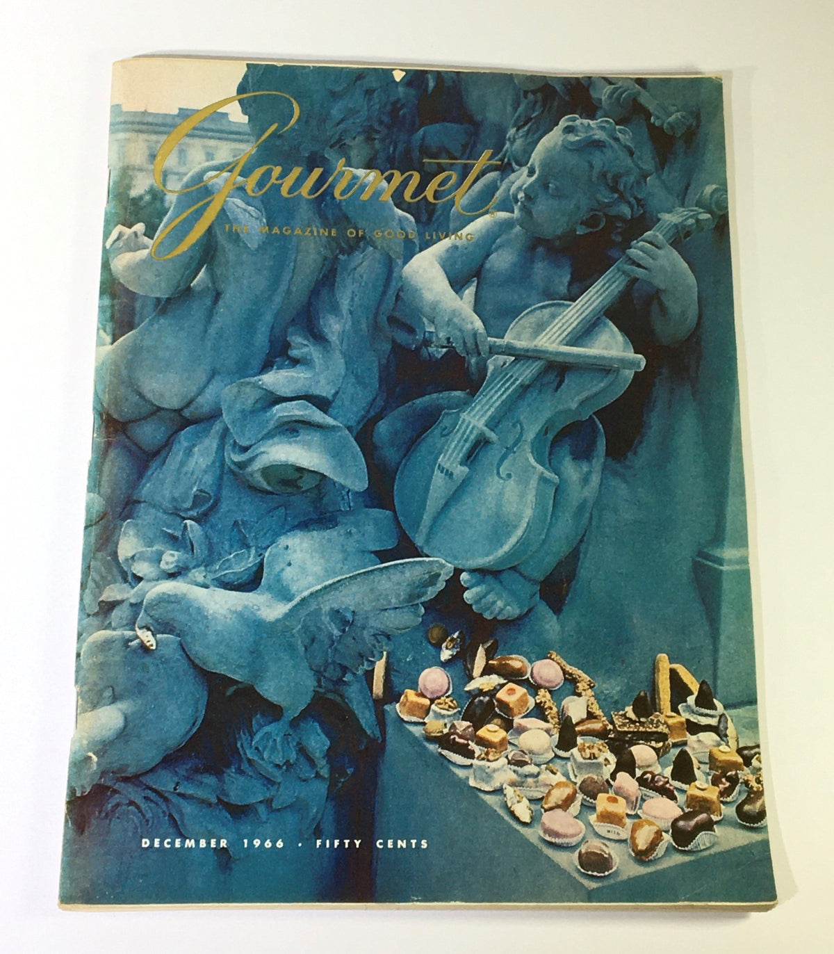 Cover of VTG Gourmet The Magazine of Good Living December 1966 featuring a classical art theme with a cherub playing a violin and an array of festive desserts, representing Weihnachten in Wien.