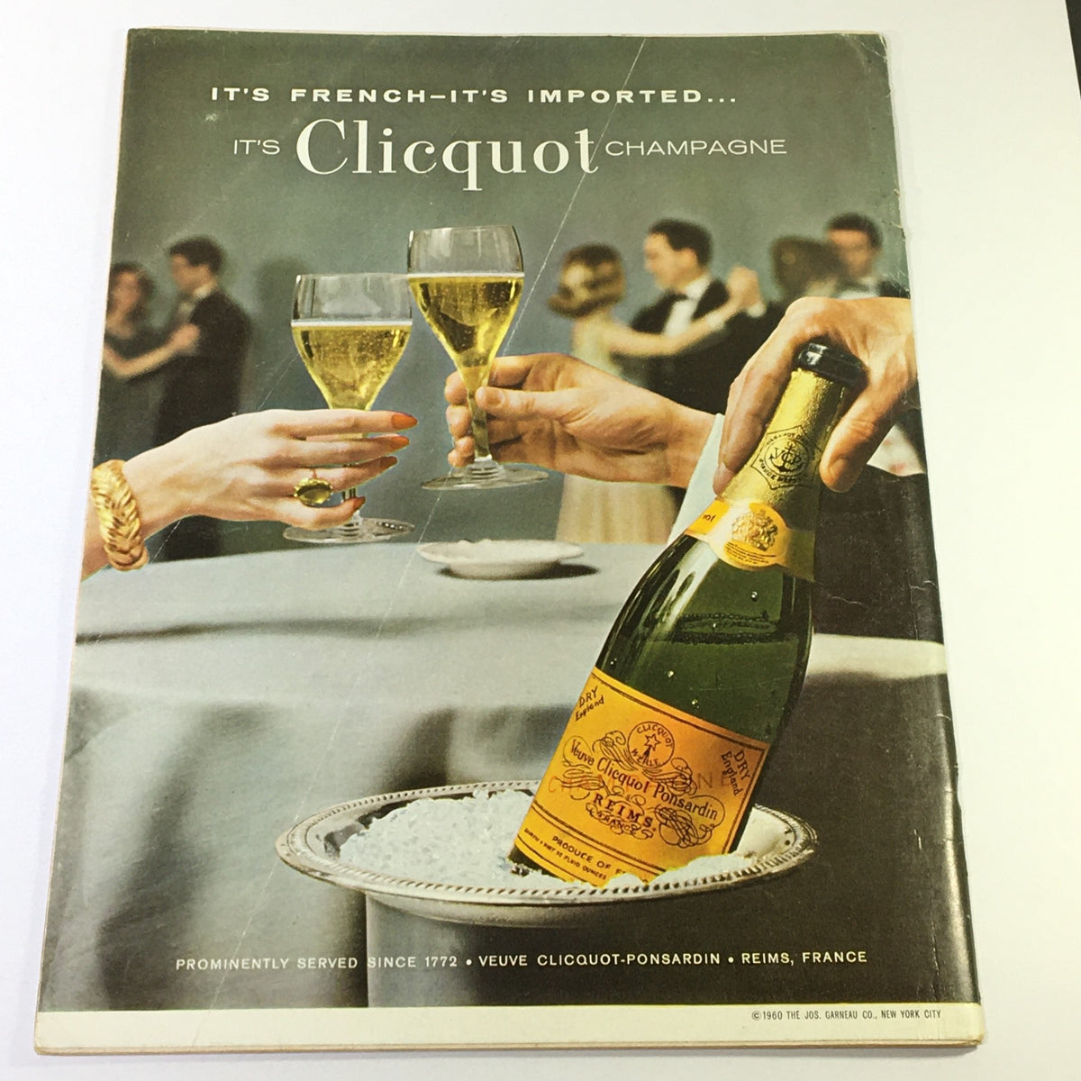 VTG Gourmet Magazine Article on Clicquot Champagne from February 1962, showcasing elegant champagne glasses and a bottle against a social gathering backdrop.
