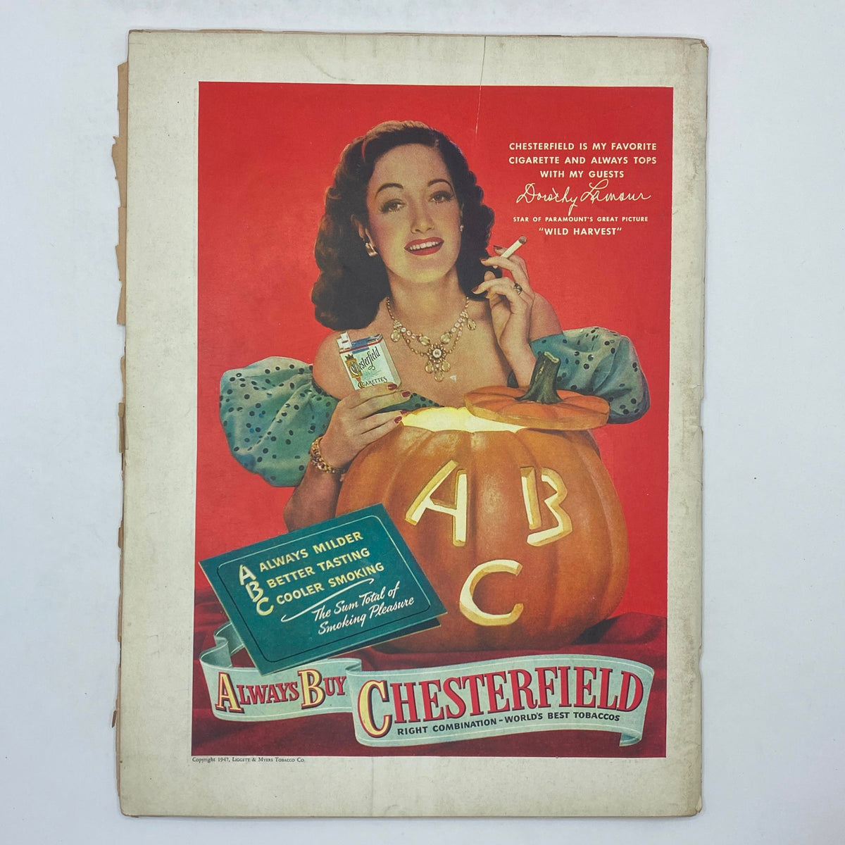 Vintage advertisement featuring a glamorous woman holding a Chesterfield cigarette beside a carved pumpkin, from The New Yorker Complete Magazine October 4, 1947 Garrett Price Cover.