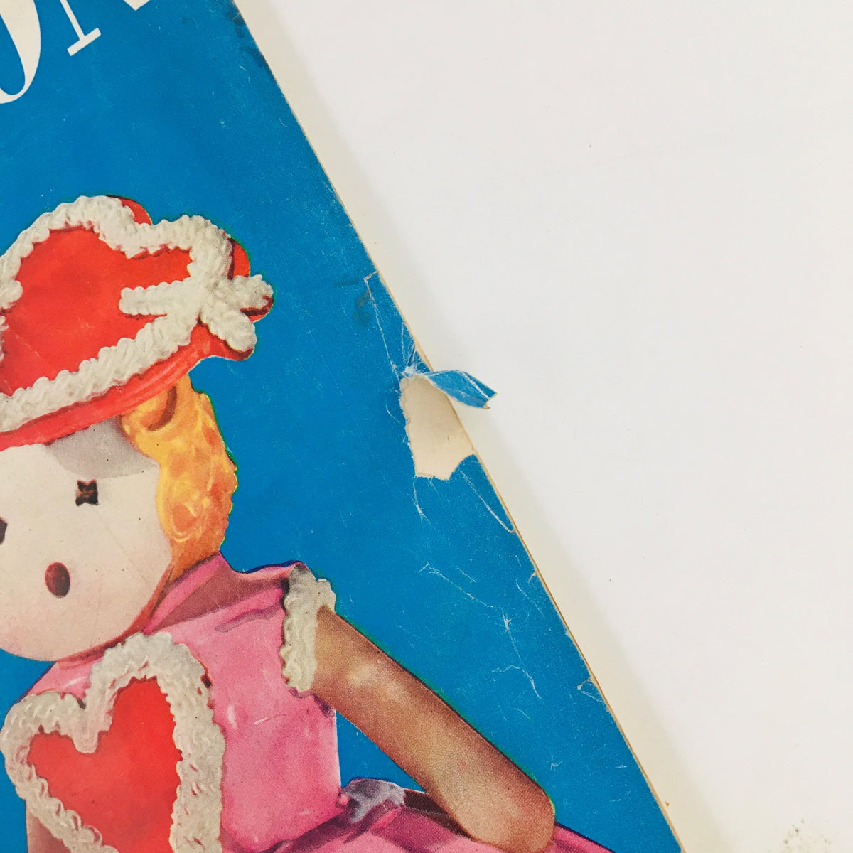 Close-up of the doll illustration from the cover of Woman's Home Companion February 1955, highlighting the pink dress and heart details.