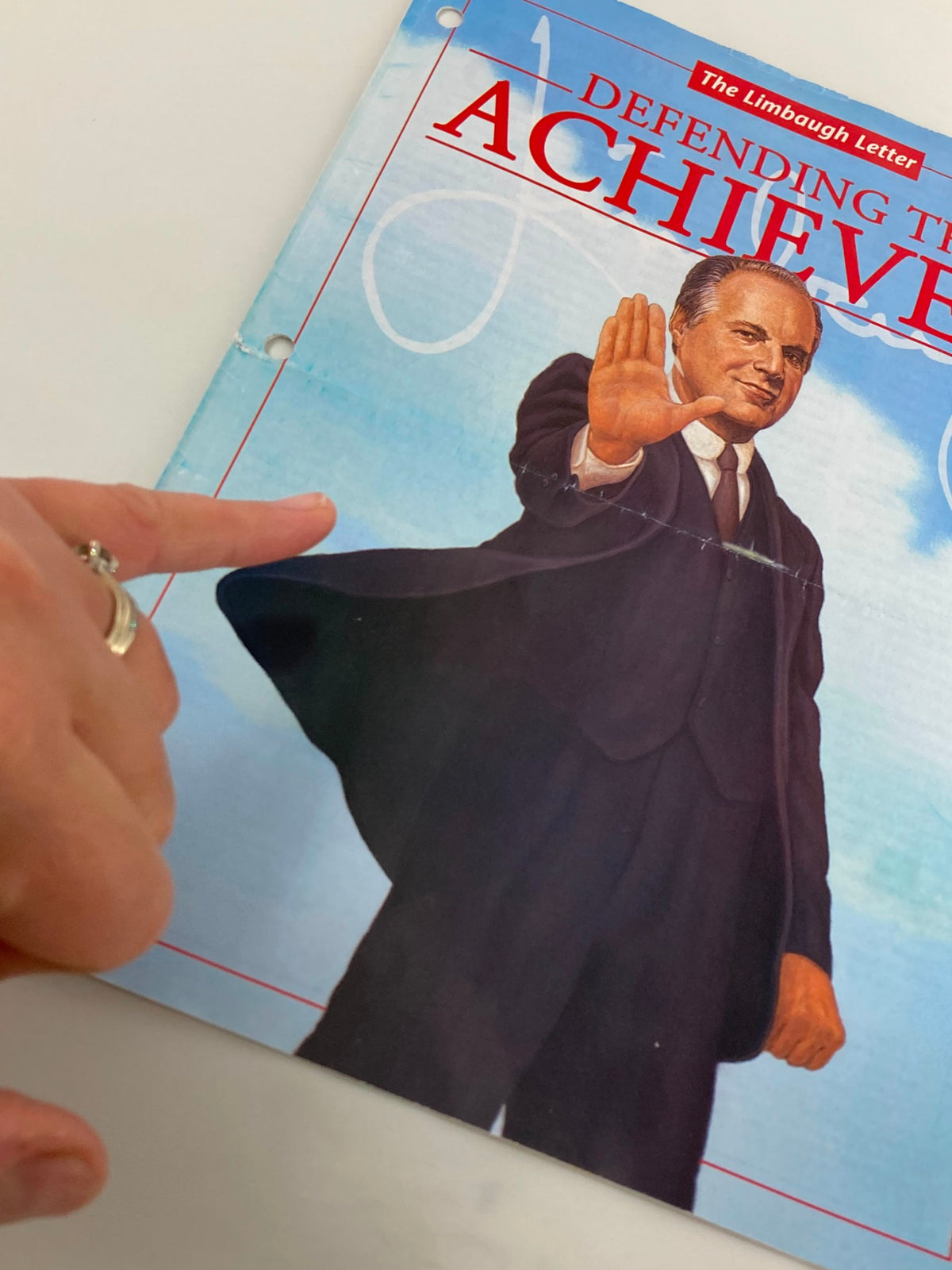 Close-up of the cover of the Rush Limbaugh Letter Newsletter Magazine from May 2002, 'Defending the Achievers', with a hand pointing at the illustration.