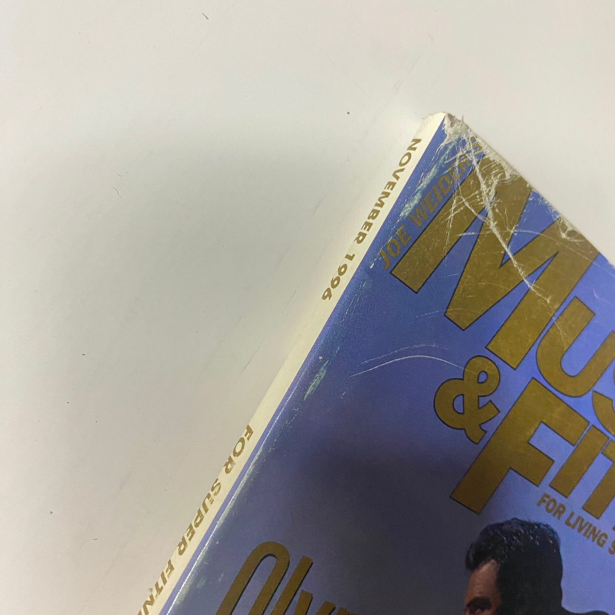 Side view of Muscle & Fitness Magazine November 1996, showing the publication date and signs of wear, indicating its vintage condition.