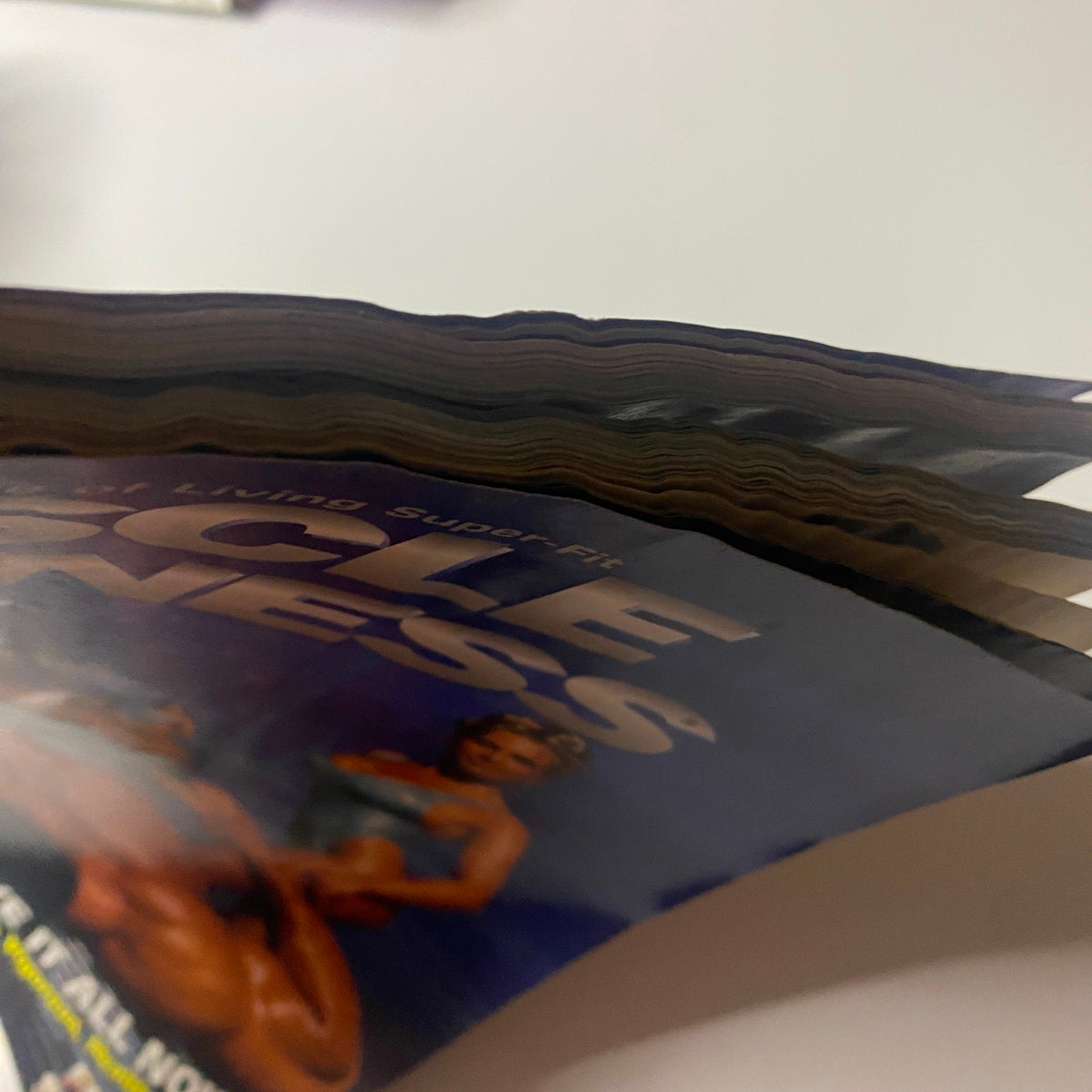 Close-up view of the spine of Muscle & Fitness Magazine July 1996, featuring a worn cover, highlighting the issue's theme on the 1996 Arnold Classic Weekend.