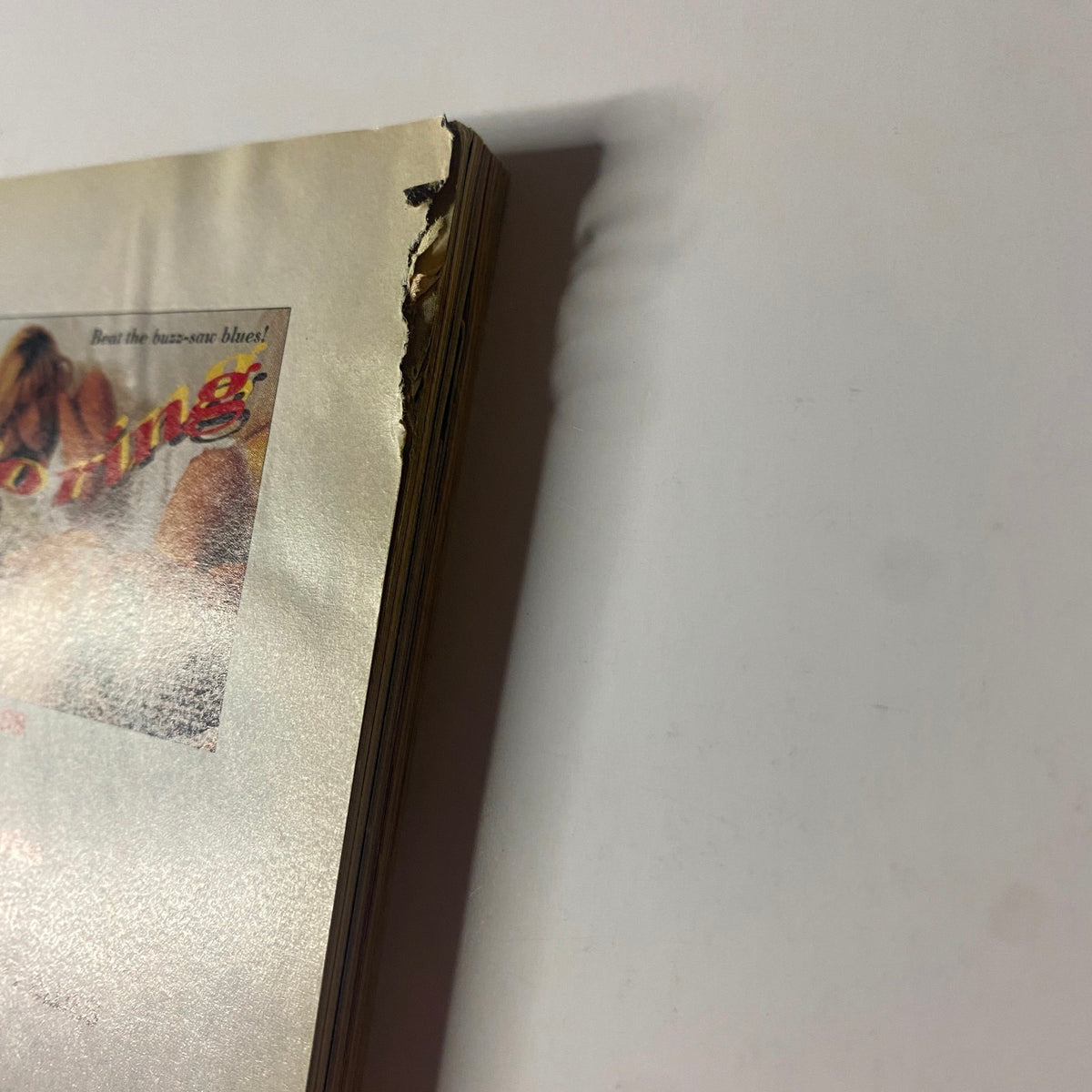 Side view of the June 1995 Muscle & Fitness Magazine, illustrating wear with torn pages, emphasizing its used condition.