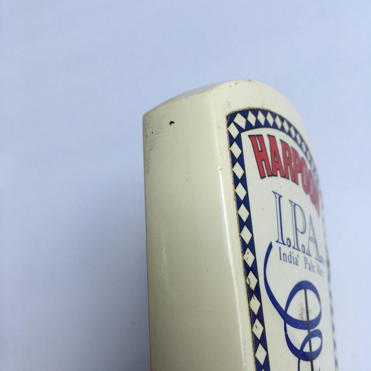 Close-up view of the Vintage Harpoon IPA Indian Pale Ale beer tap handle, showcasing minor wear details on the edge.