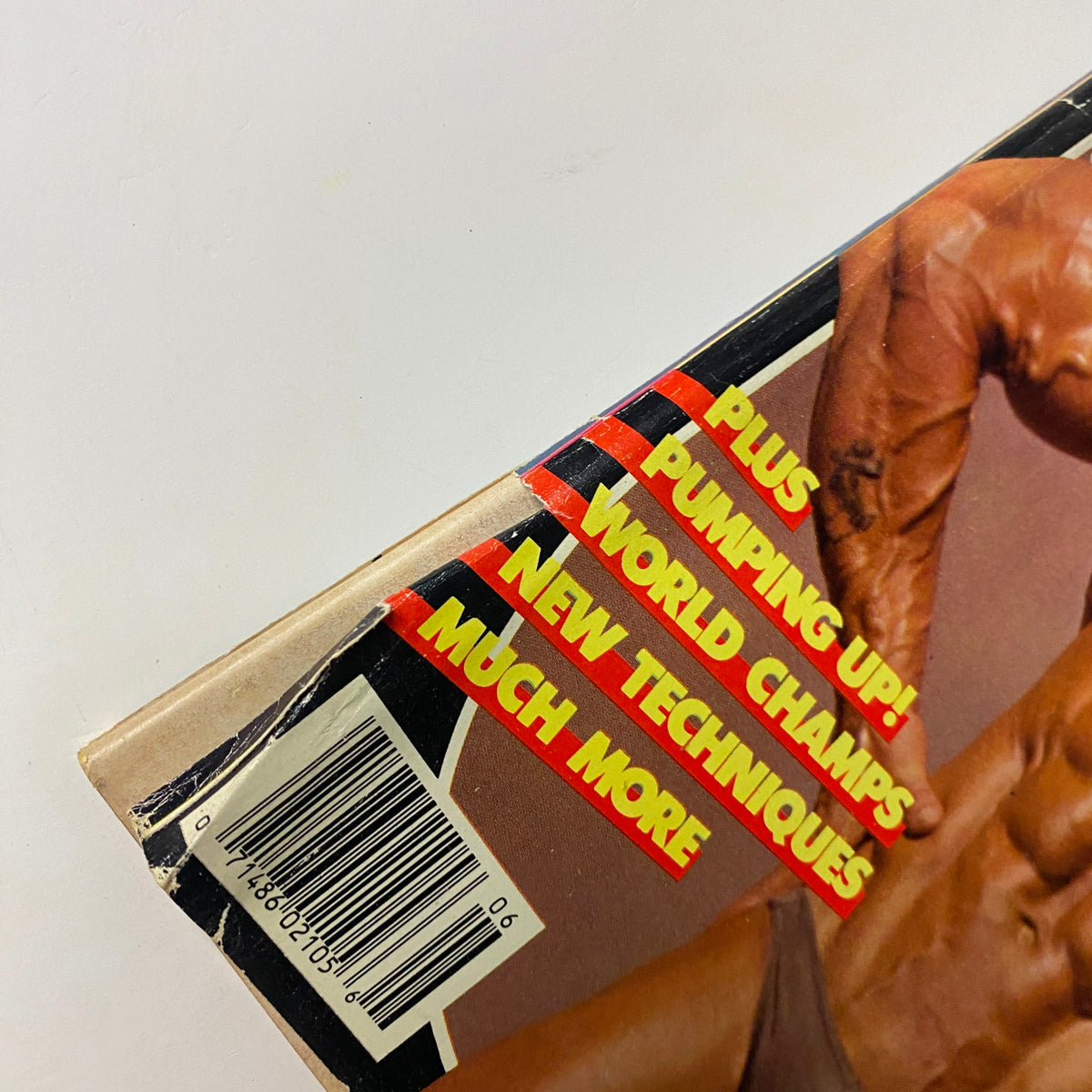 Close-up shot of the spine of MuscleMag International Magazine June 1986, highlighting the text 'PLUS PUMPING UP! WORLD CHAMP'S NEW TECHNIQUES MUCH MORE' for bodybuilding enthusiasts.