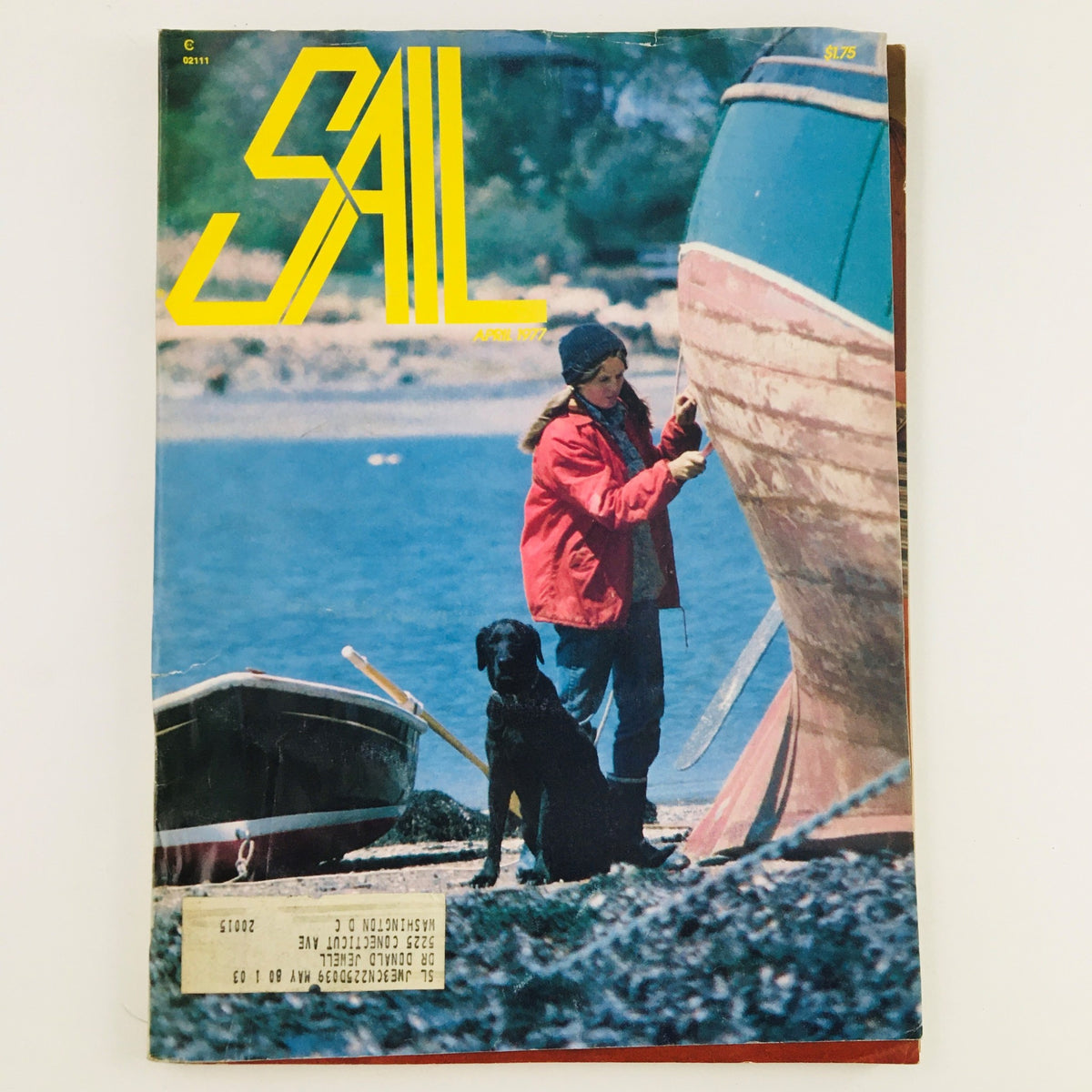 Cover of Sail Magazine April 1977 featuring an article titled 'Kate Burke Works Against Time and Tide To Seam Bottom' with a woman in a red jacket working on a boat alongside a dog.
