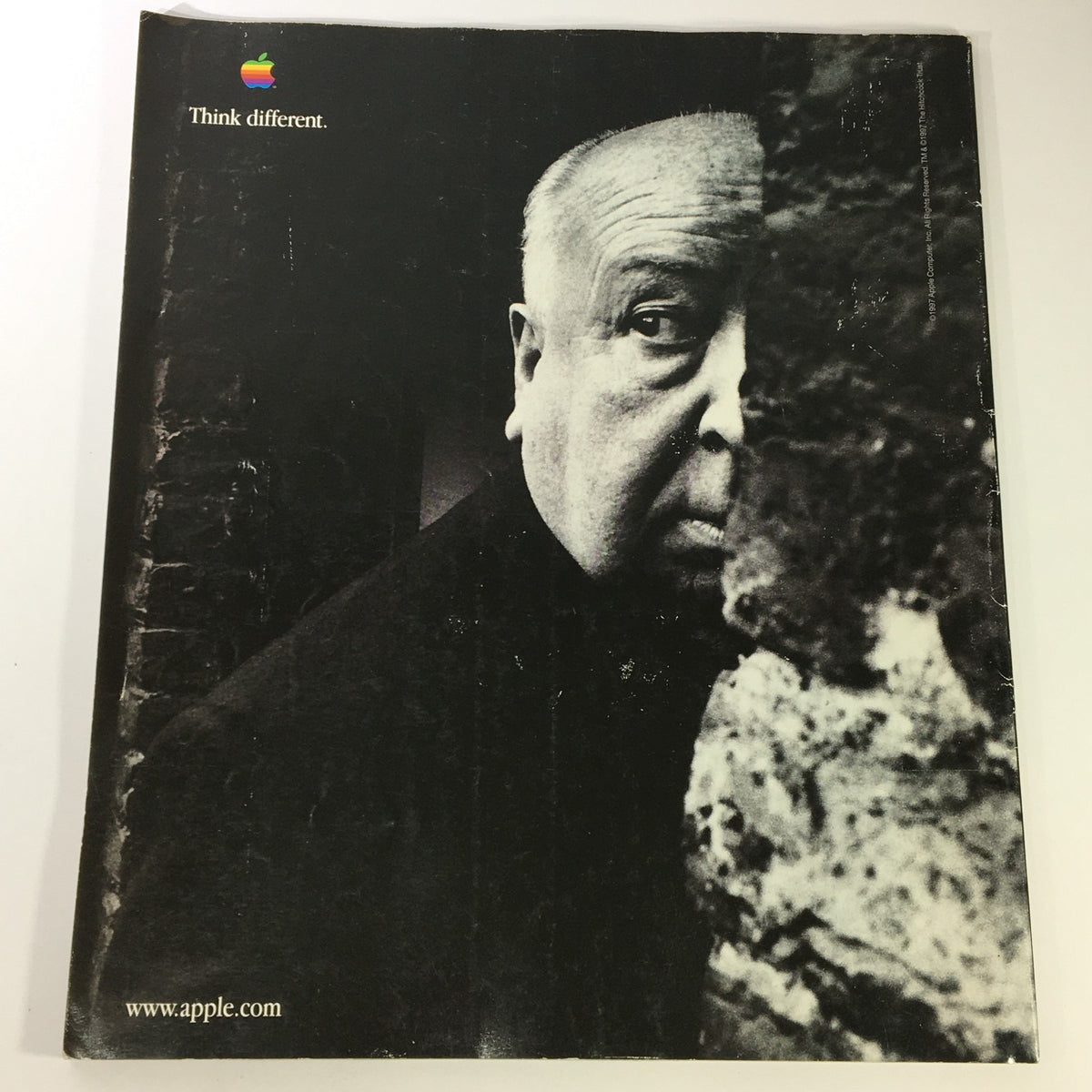 Black and white advertisement featuring Alfred Hitchcock with the Apple logo and the slogan 'Think different.', reflecting the influence of classic cinema on modern technology.