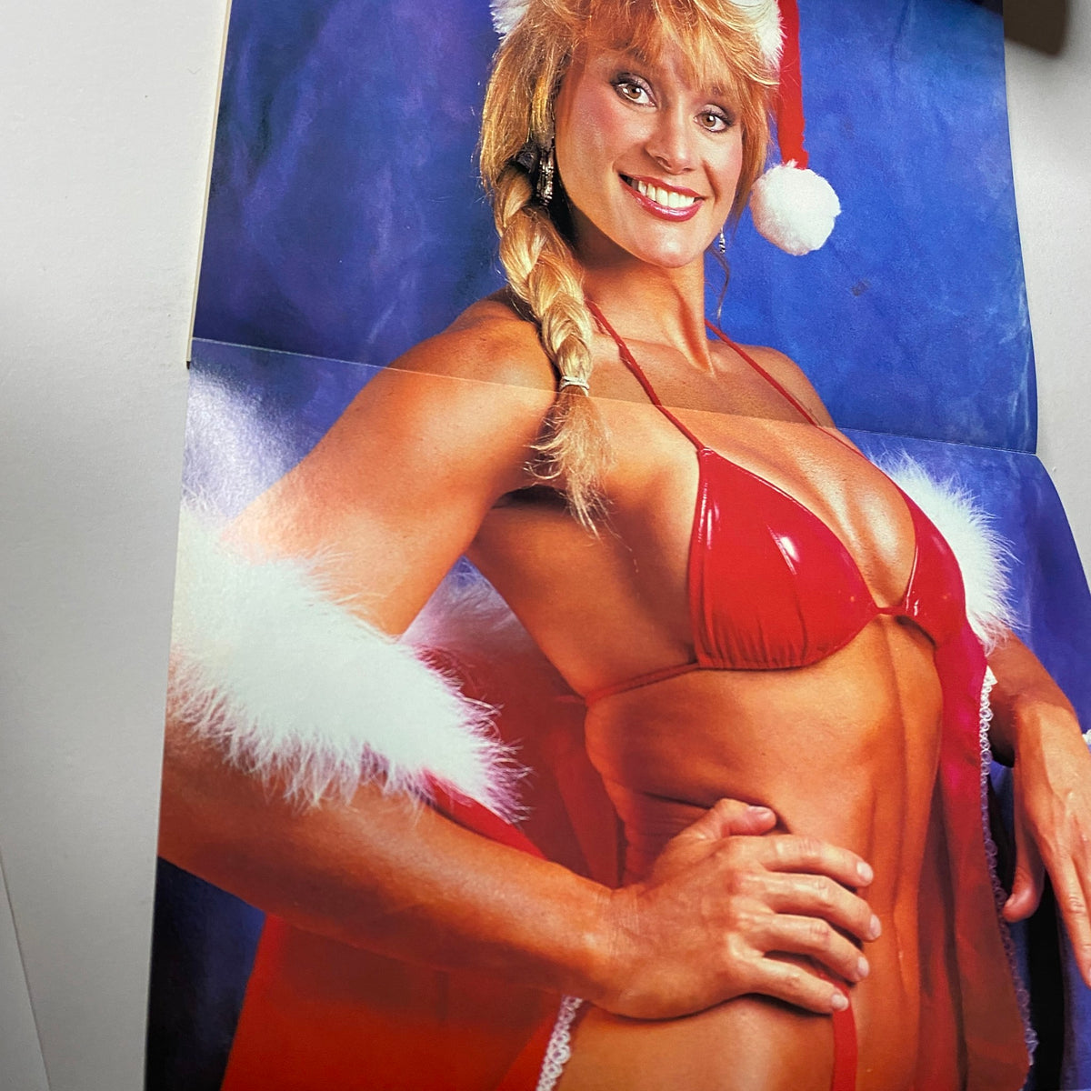 Centerfold poster from Muscular Development Magazine December 1990, featuring a model in a festive red swimsuit and Santa hat, promoting fitness and bodybuilding culture.