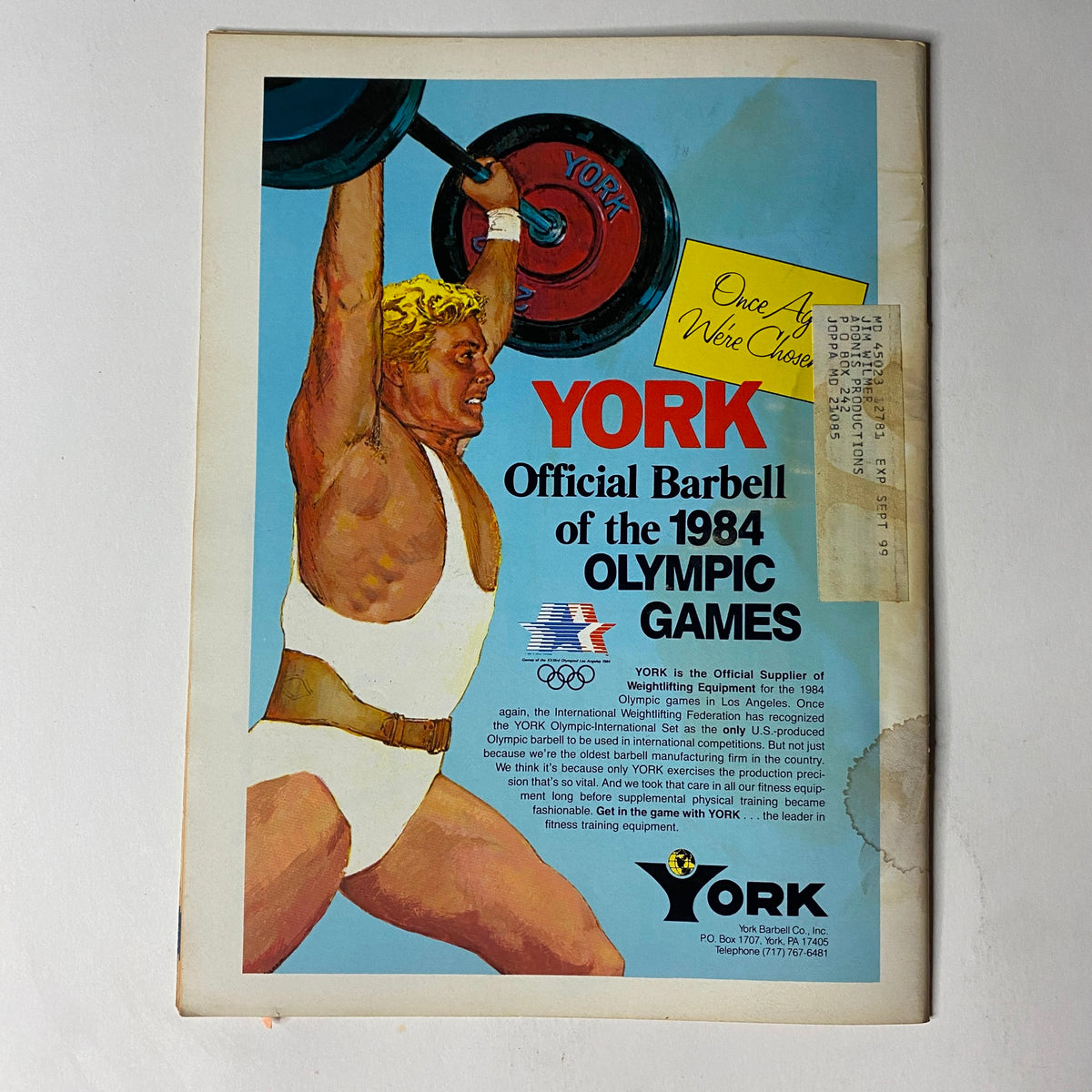 Advertisement page in Muscular Development Magazine December 1983 featuring York Barbell, promoting official equipment for the 1984 Olympic Games.