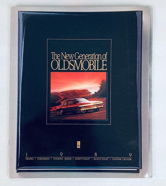 1989 Oldsmobile New Generation Dealer Showroom Sales Brochure Cover featuring a scenic sunset view with a classic Oldsmobile vehicle displayed prominently.
