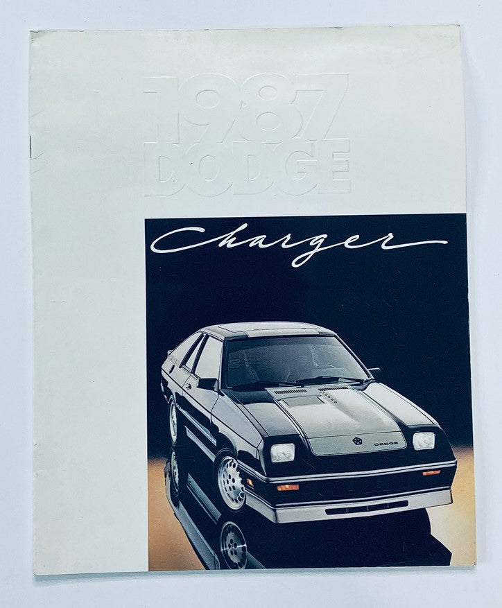 1987 Dodge Charger Dealer Showroom Sales Brochure Guide Catalog featuring a sleek black Dodge Charger on the cover with a reflective surface, showcasing the iconic design of this classic vehicle.
