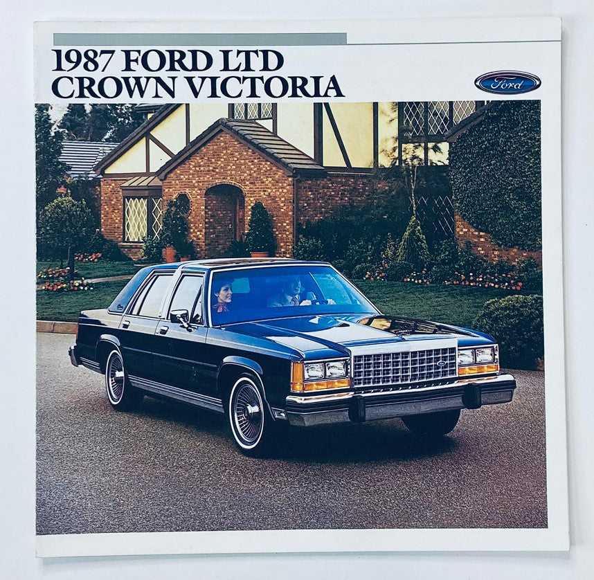 Front view of the 1987 Ford LTD Crown Victoria Dealer Showroom Sales Brochure with a black vehicle parked in a residential setting. This brochure is part of the 1987 Ford LTD Crown Victoria Dealer Showroom Sales Brochure Guide Catalog, highlighting the classic car's design and features.