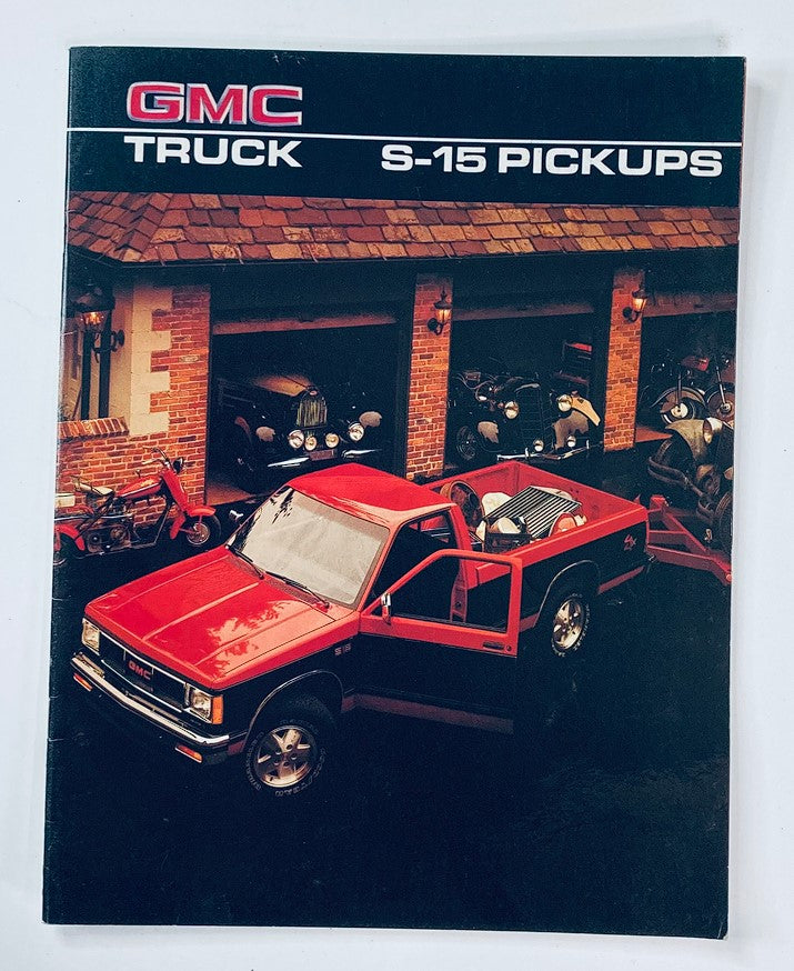 1986 GMC S-15 Pickups Truck Dealer Showroom Sales Brochure Guide Catalog featuring a red truck parked in front of a garage with classic cars.