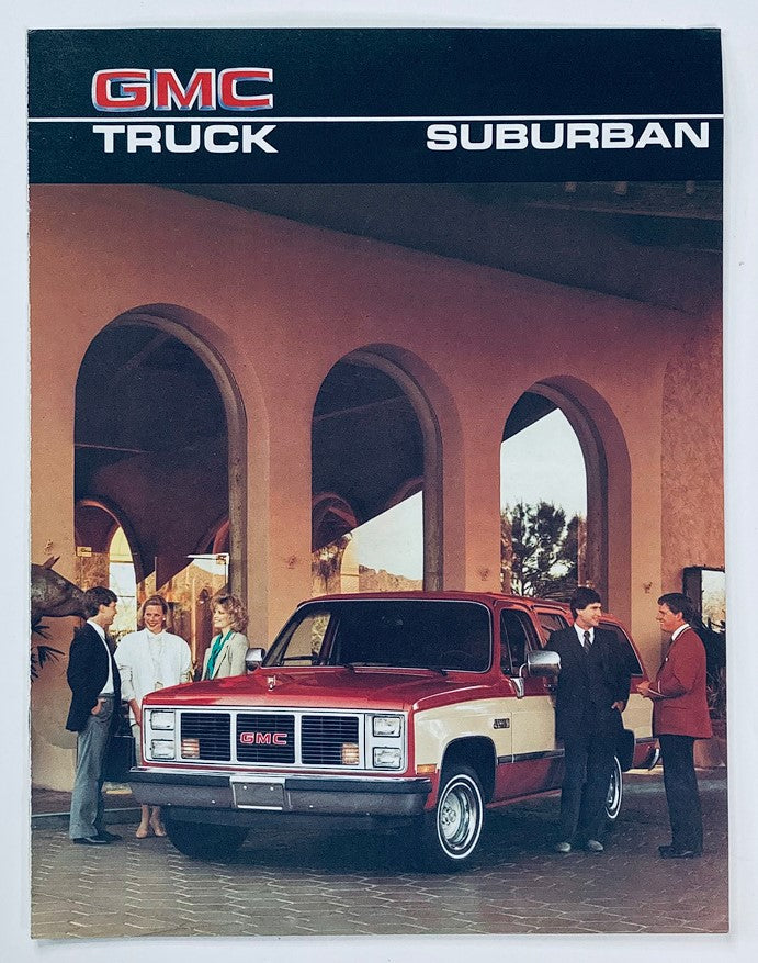 1986 GMC Truck Suburban Dealer Showroom Sales Brochure featuring a stylish red GMC Suburban in a showroom with people discussing the vehicle. This catalog showcases the 1986 GMC Truck Suburban features and design.