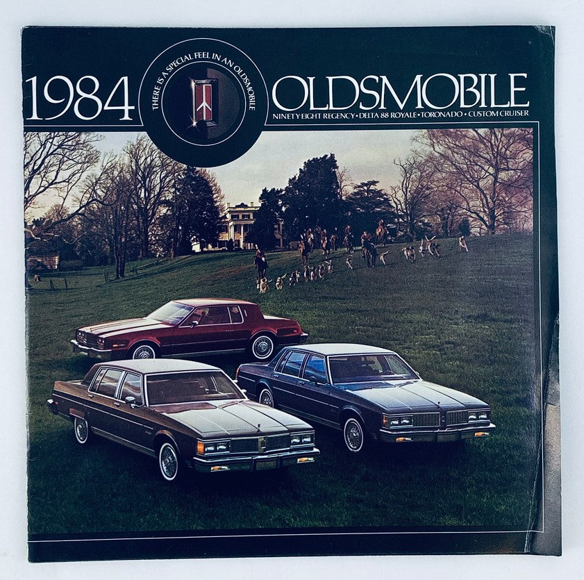 1984 Oldsmobile Delta 88 Royale Dealer Showroom Sales Brochure featuring vintage cars parked on a scenic lawn, showcasing the design and features of the Oldsmobile models.