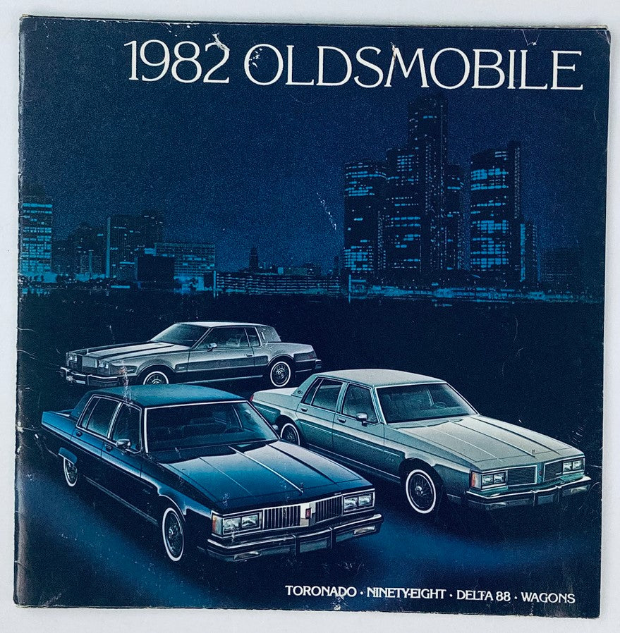 1982 Oldsmobile Full Line Dealer Showroom Sales Brochure featuring a stylish illustration of the 1982 Oldsmobile models including Toronado, Ninety-Eight, Delta 88 and Wagons set against a city skyline backdrop.
