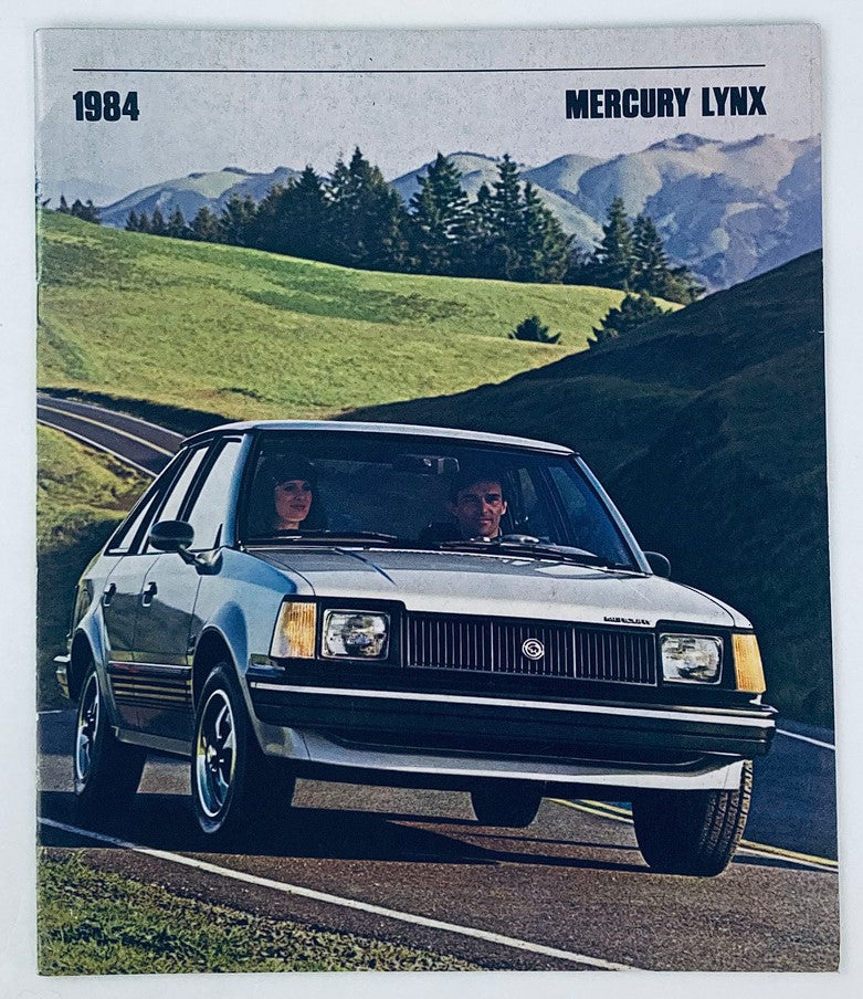 1984 Mercury Lynx Full Line Dealer Showroom Sales Brochure Guide Catalog featuring a silver Mercury Lynx car driving on a scenic road with mountains in the background.