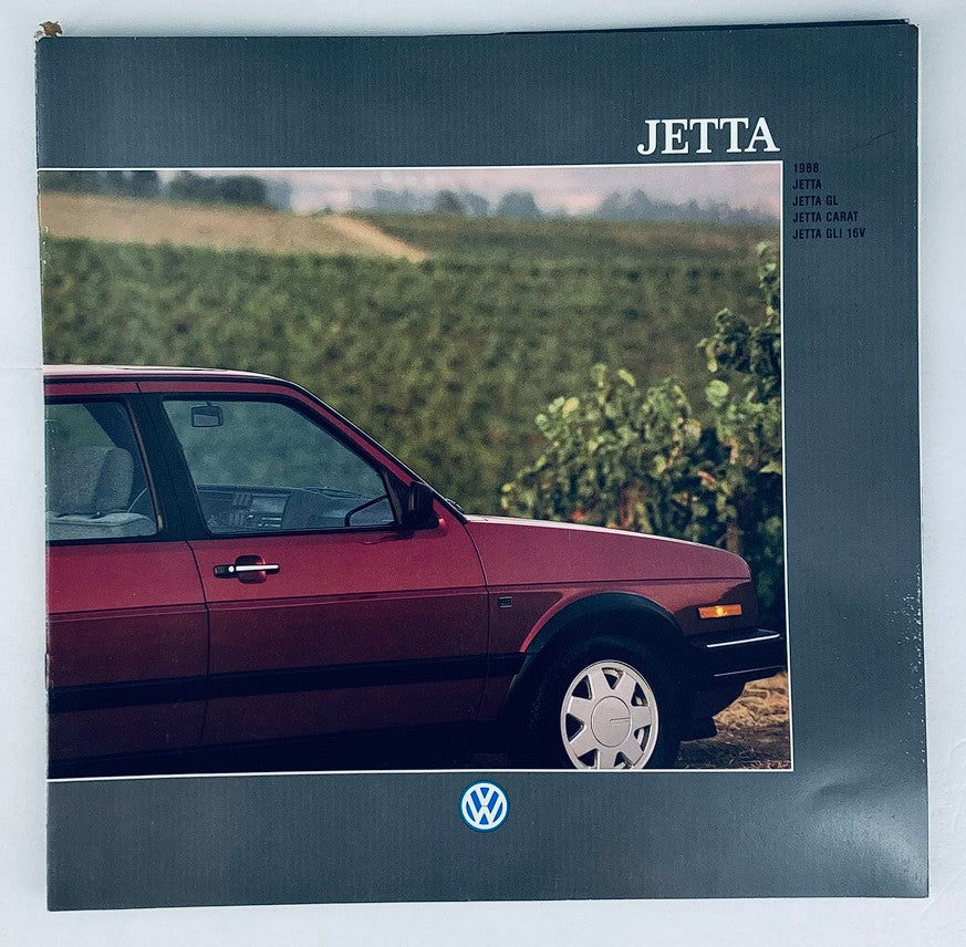 Cover of the 1988 Volkswagen Jetta Dealer Showroom Sales Brochure Guide Catalog featuring a side view of a red Volkswagen Jetta against a verdant background, highlighting the vehicle's sleek design.