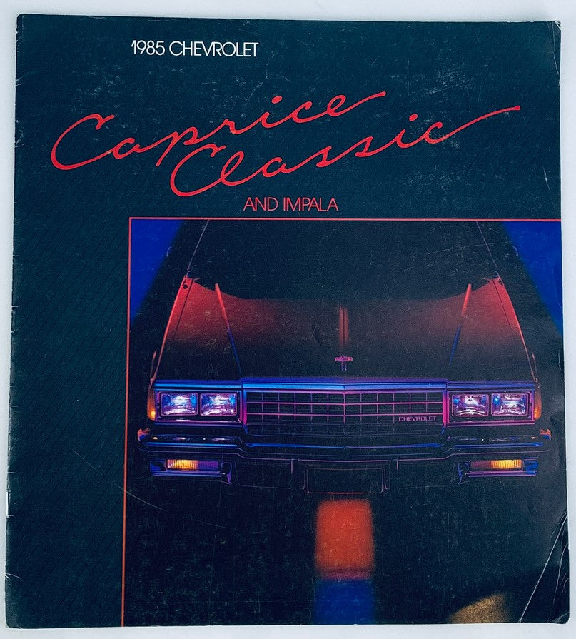 1985 Chevrolet Caprice Classic Dealer Showroom Sales Brochure Guide Catalog cover featuring the classic car in a dark setting, highlighting its front design with headlights on, perfect for collectors and automotive enthusiasts.